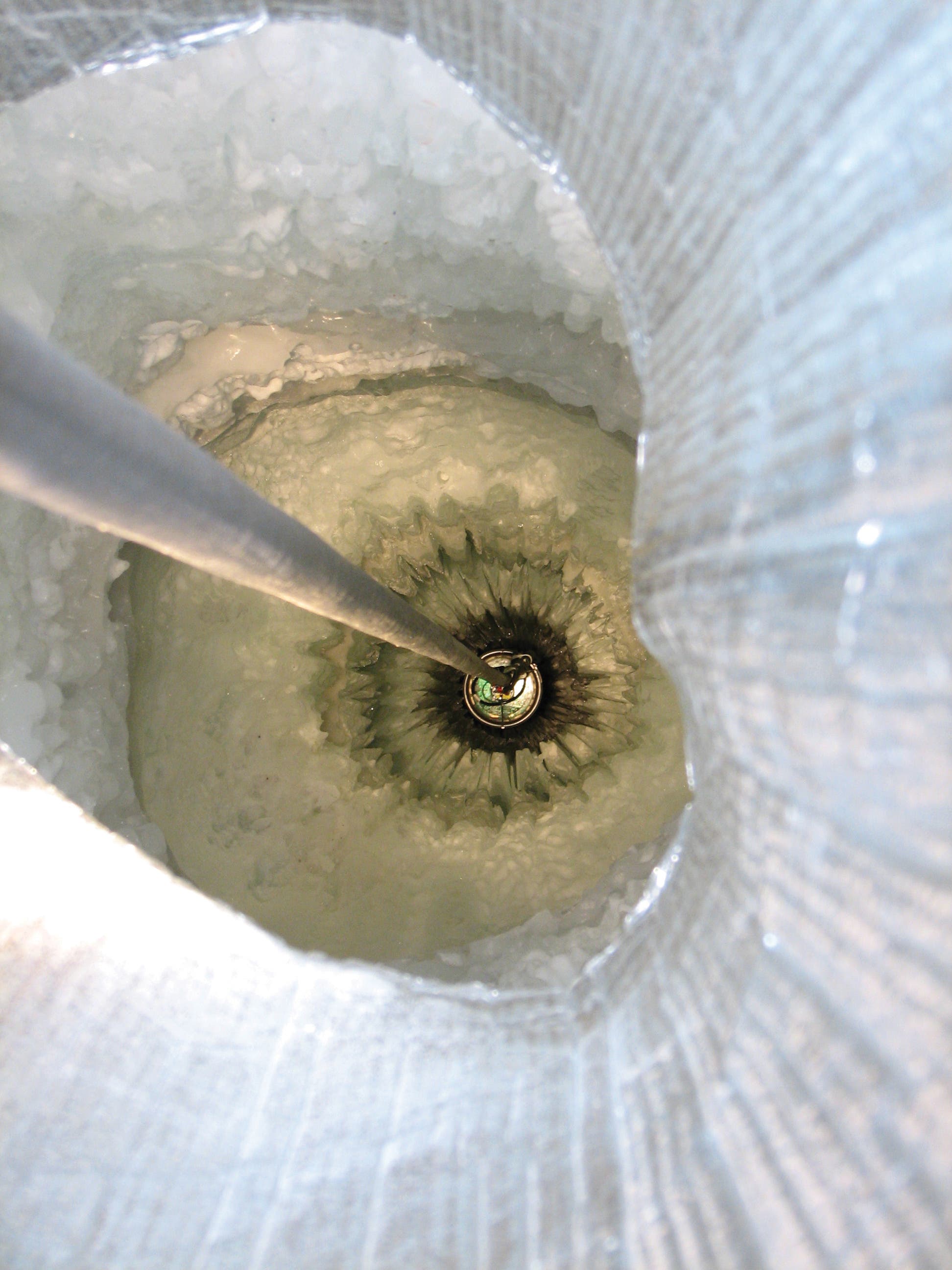 ein DOM-Sensor wird in ein IceCube-Bohrloch hinabgelassen