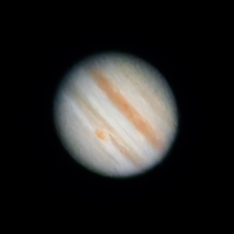 Das Bild zeigt den Planeten Jupiter mit seinen charakteristischen Wolkenbändern und dem Großen Roten Fleck. Die Wolkenbänder sind in verschiedenen Brauntönen sichtbar, die sich horizontal über die Oberfläche des Planeten erstrecken. Der Große Rote Fleck, ein markantes Sturmgebiet, ist als rötlicher Fleck auf der linken Seite des Planeten erkennbar. Der Hintergrund ist schwarz, was den Fokus auf den Planeten lenkt.