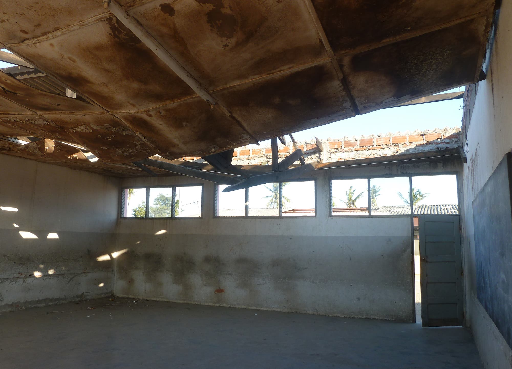 Blick in einen beschädigten Klassenraum mit zerstörtem Dach.