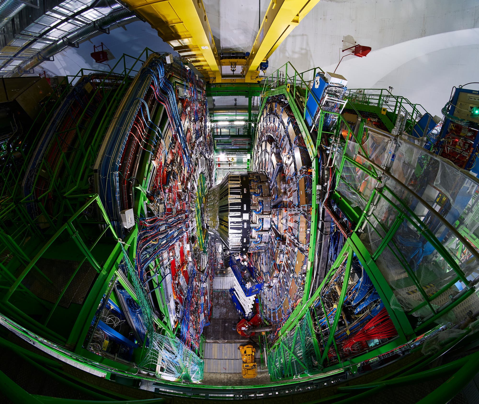 Blick von oben in die Kaverne des gewaltigen CMS-Detektors, in dessen Zentrum mehrere Personen Bauteile montieren