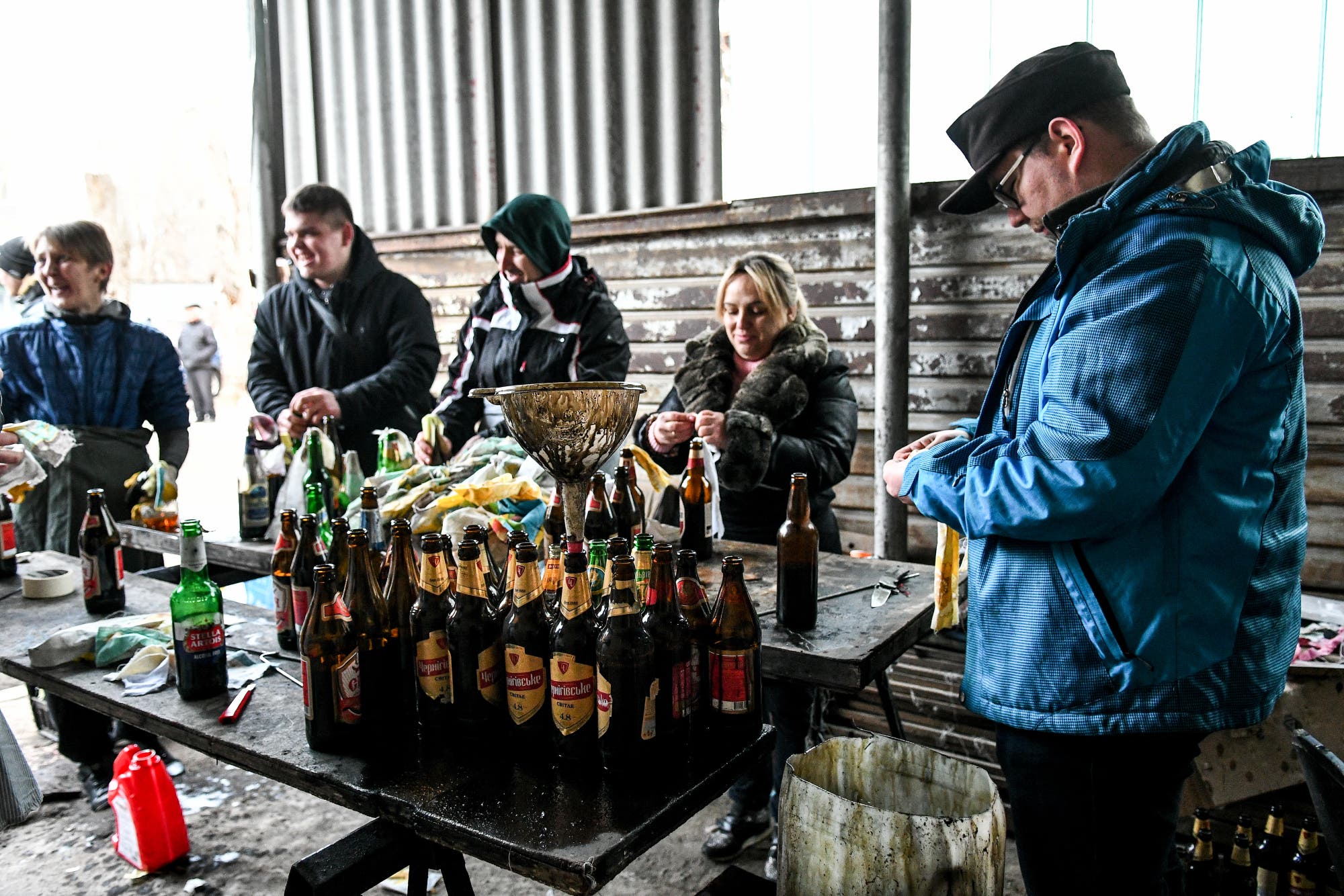 Menschen in dicken Jacken füllen Bierflaschen mit brennbarer Flüssigkeit.