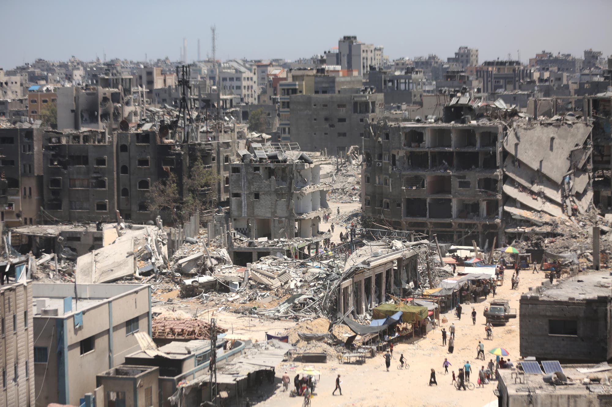 Zerstörte Gebäude im Gaza-Streifen, dazwischen laufen Menschen.
