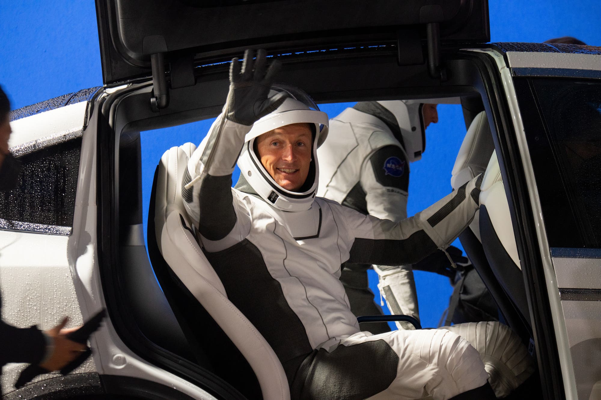Matthias Maurer winkt aus einem weißen Tesla auf dem Weg zur SpaceX-Kapsel