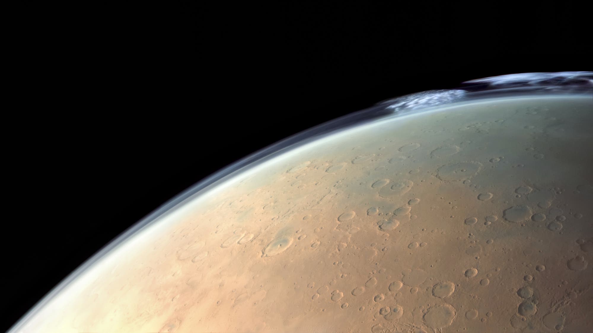 Eine detaillierte Aufnahme der Marsoberfl&auml;che, die Krater und eine d&uuml;nne Wolkenschicht am Horizont zeigt. Die Oberfl&auml;che erscheint r&ouml;tlich braun mit zahlreichen Einschlagkratern unterschiedlicher Gr&ouml;&szlig;e. Der schwarze Weltraum bildet den Hintergrund. Das Bild vermittelt einen Eindruck von der geologischen Beschaffenheit und Atmosph&auml;re des Mars.