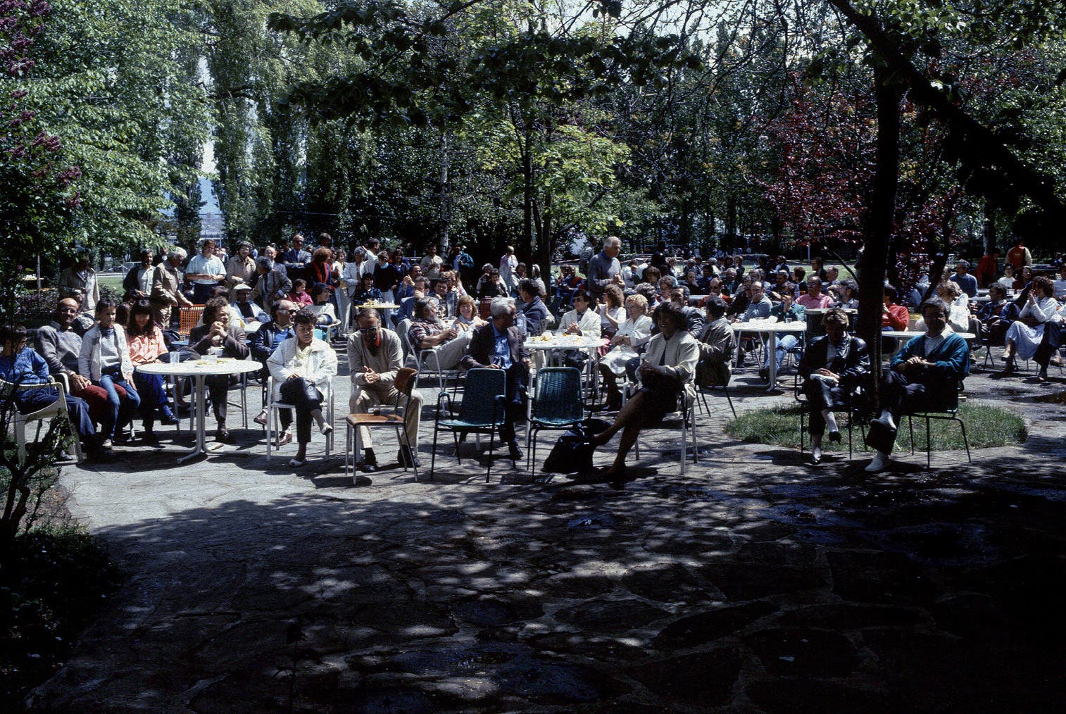 Auf der Terrasse vor dem Restaurant des CERN sitzen zahlreiche Menschen bei angeregten Unterhaltungen in der Sonne