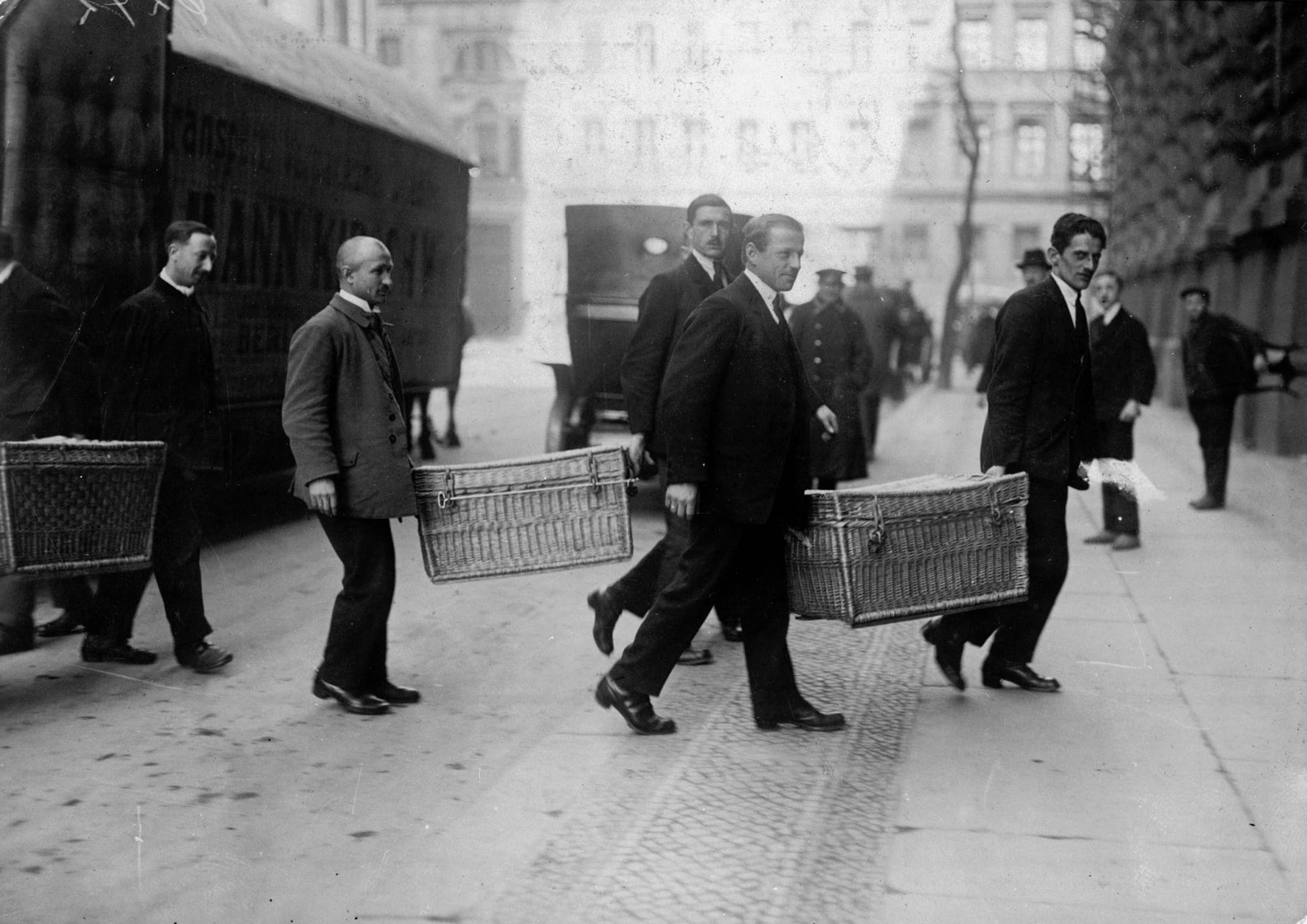 Männer transportieren Geld in Körben zu einer Bank in Berlin im Jahr 1923.