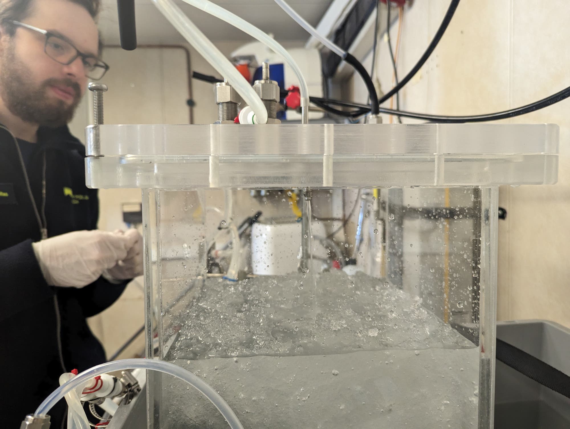 Ein Forscher vor einem Glasbehälter voller Schneematsch.