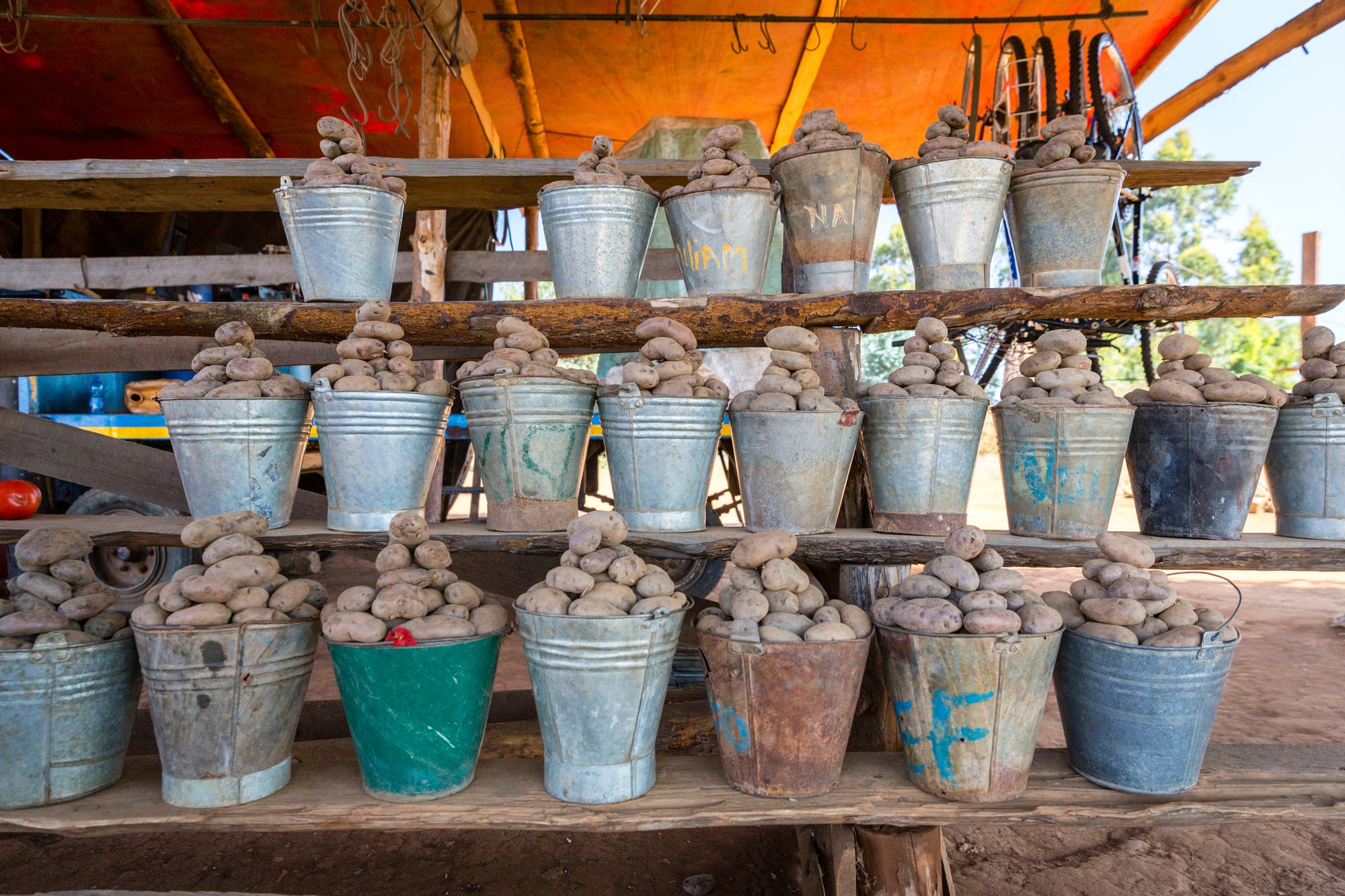 Ein Lebensmittelmarkt in Malawi, Südostafrika. In einem Regal werden Eimer, gefüllt mit frischen Kartoffeln, zum Verkauf angeboten.