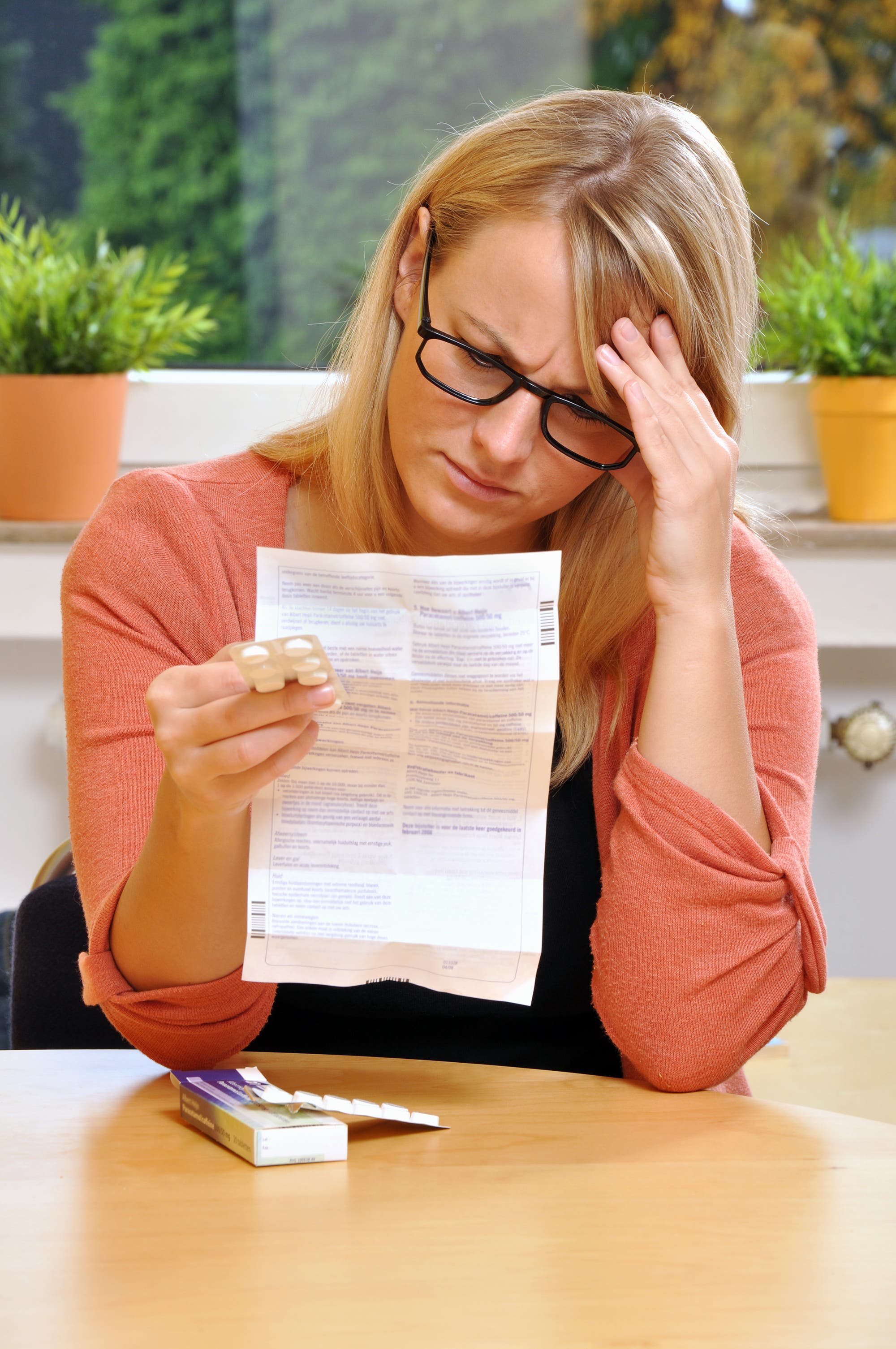 Eine Frau liest mit ernster Miene einen Beipackzettel