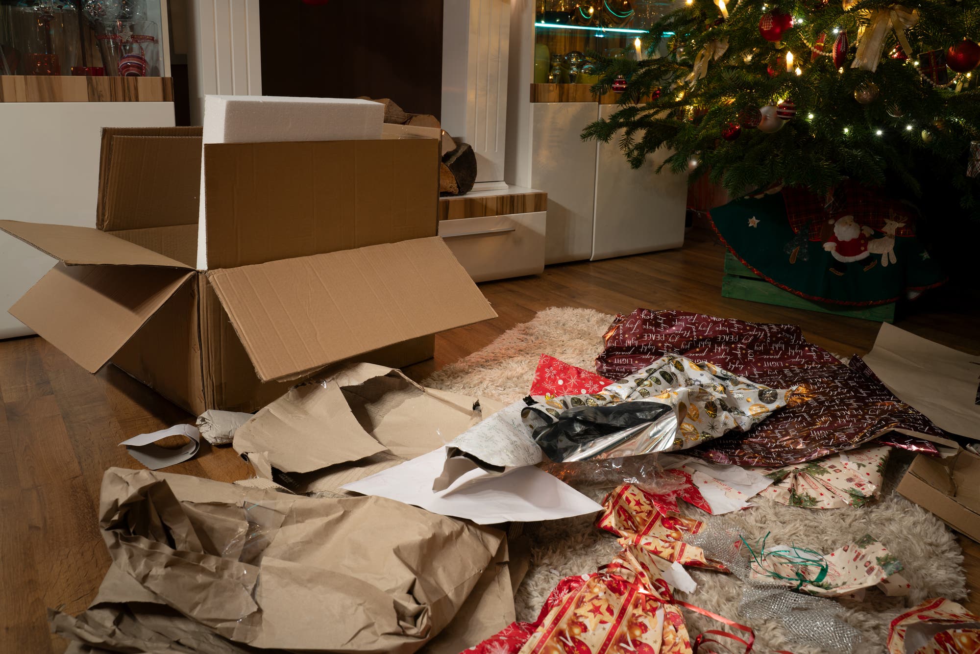 Ein Haufen zerrissenes Geschenkpapier liegt unterm Weihnachtsbaum