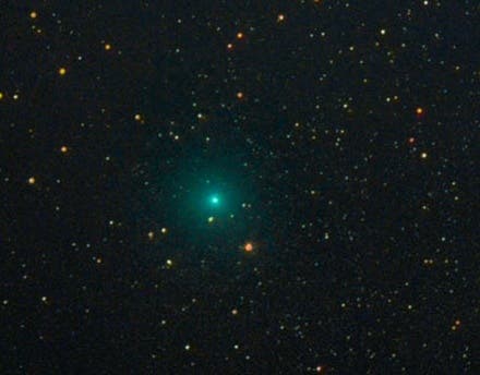 Frente con un fondo negro con estrellas, un cometa brillante pasa con la cola.