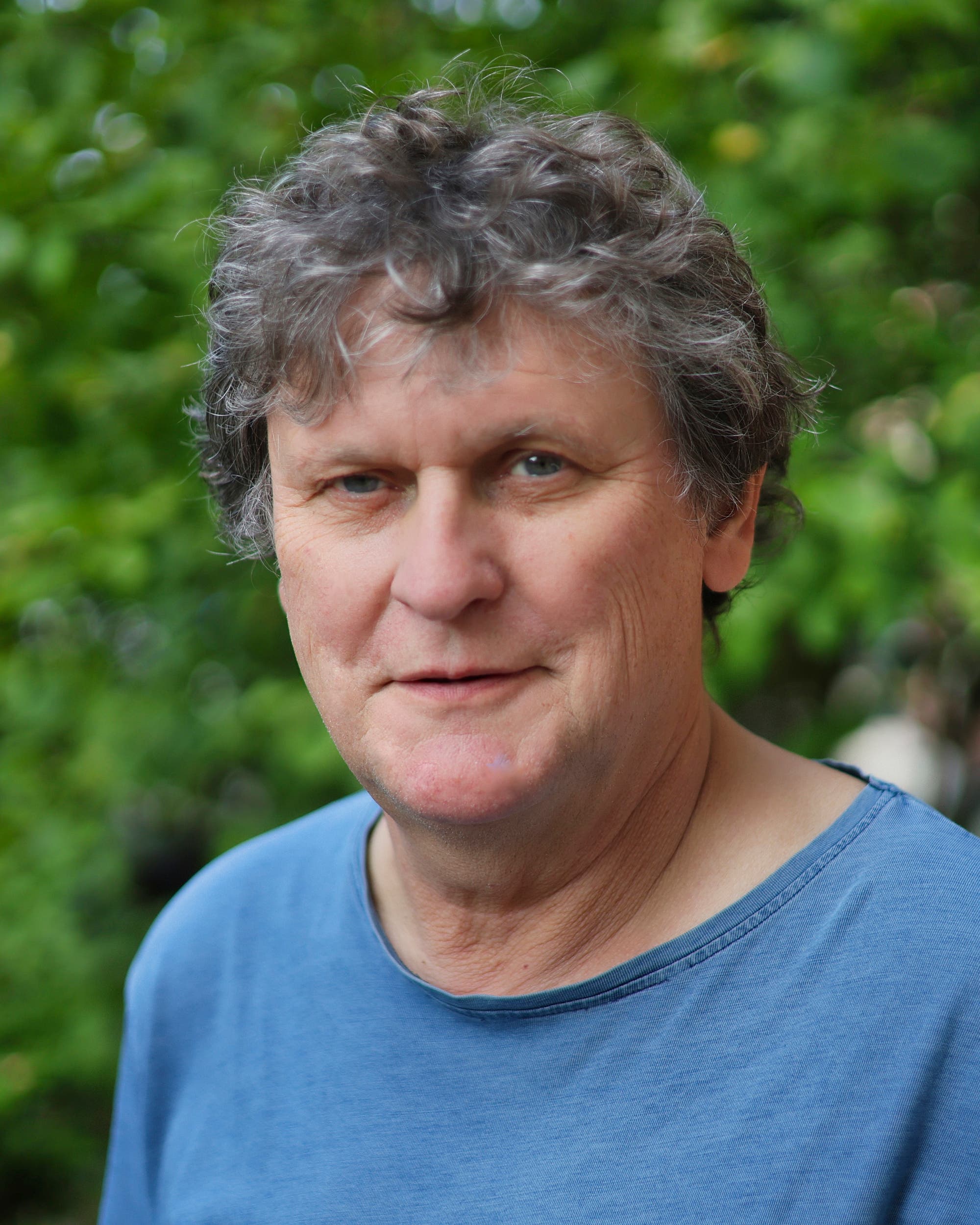 Älterer Mann mit Locken im blauen T-Shirt