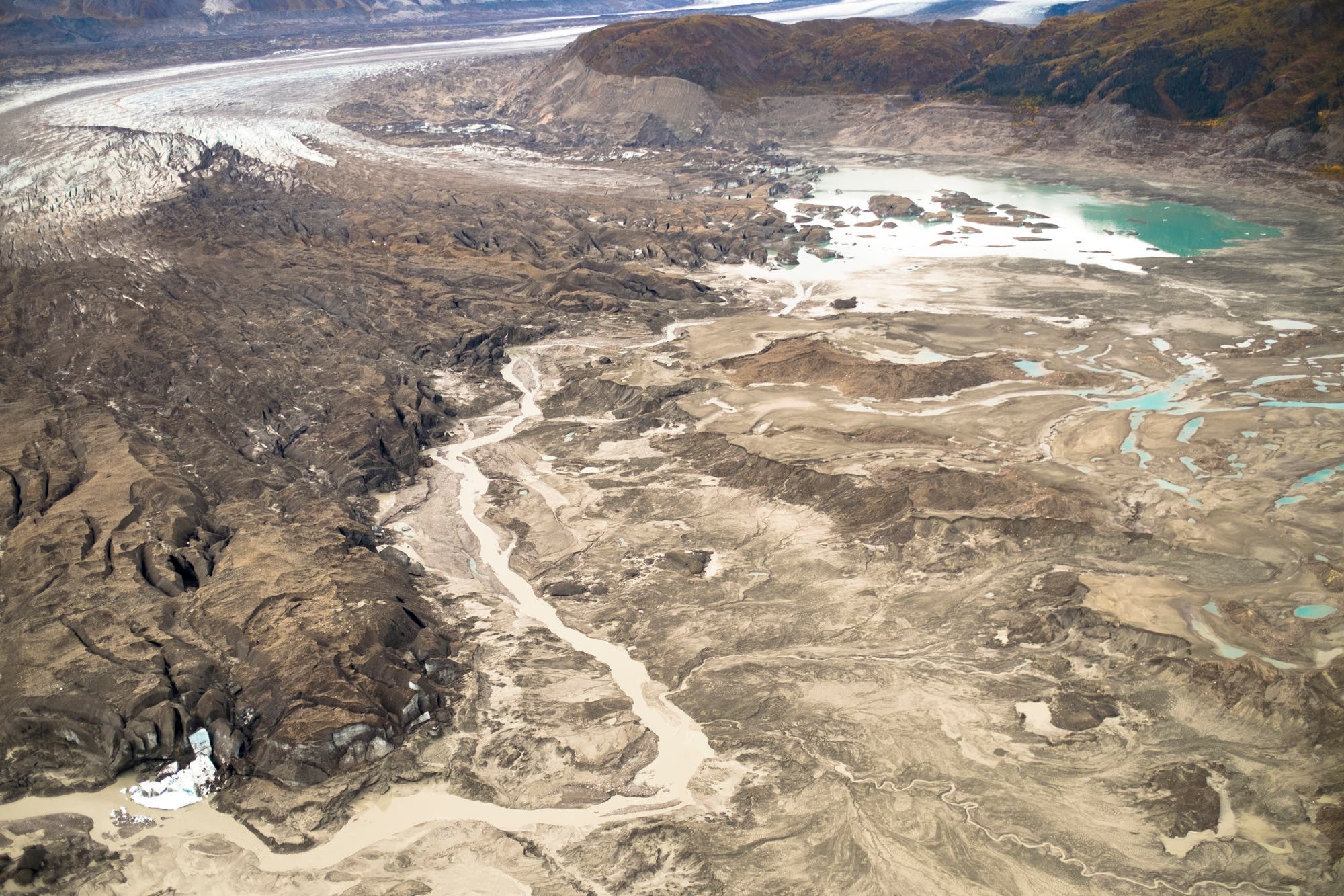 Ein schmaler Kanal kreuzt Ödland vor der Gletscherzunge, das der Gletscher erst kürzlich freigegeben hat.
