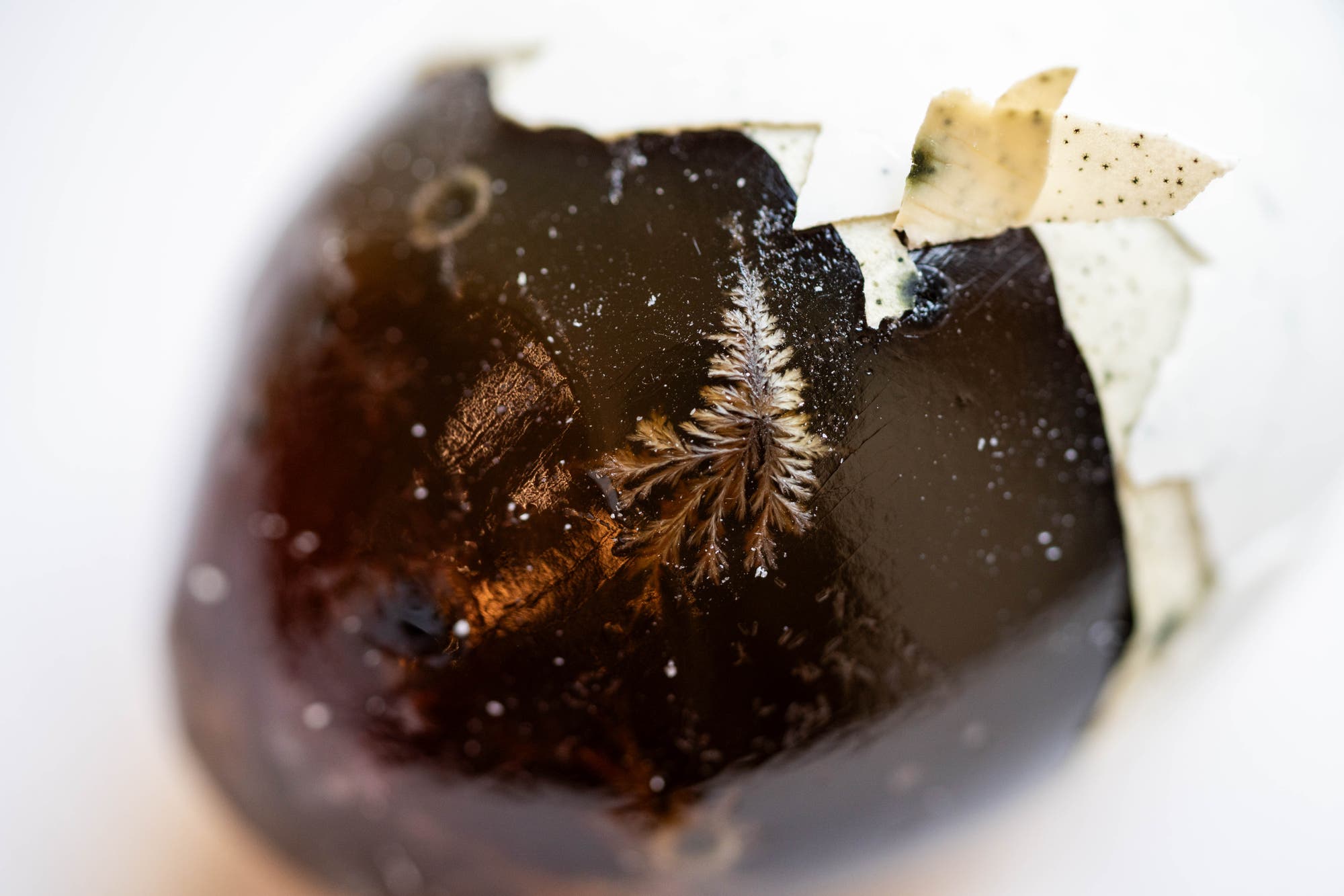 Ein geschältes, schwarzes Ei mit einer glänzenden Oberfläche, auf der eine kristallartige Struktur sichtbar ist. Die Eierschale ist teilweise entfernt und zeigt eine kontrastreiche Textur. Dieses Bild zeigt ein &raquo;Century Egg&laquo;, eine traditionelle chinesische Delikatesse.
