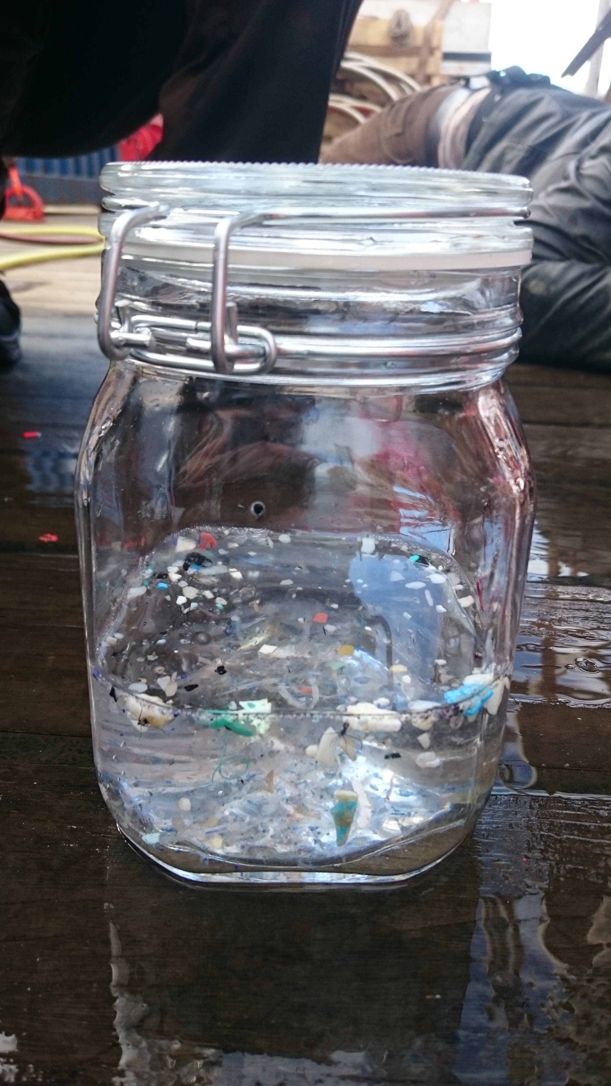 Ein Einmachglas mit Wasser enthält verschiedenste kleine Plastikteilchen