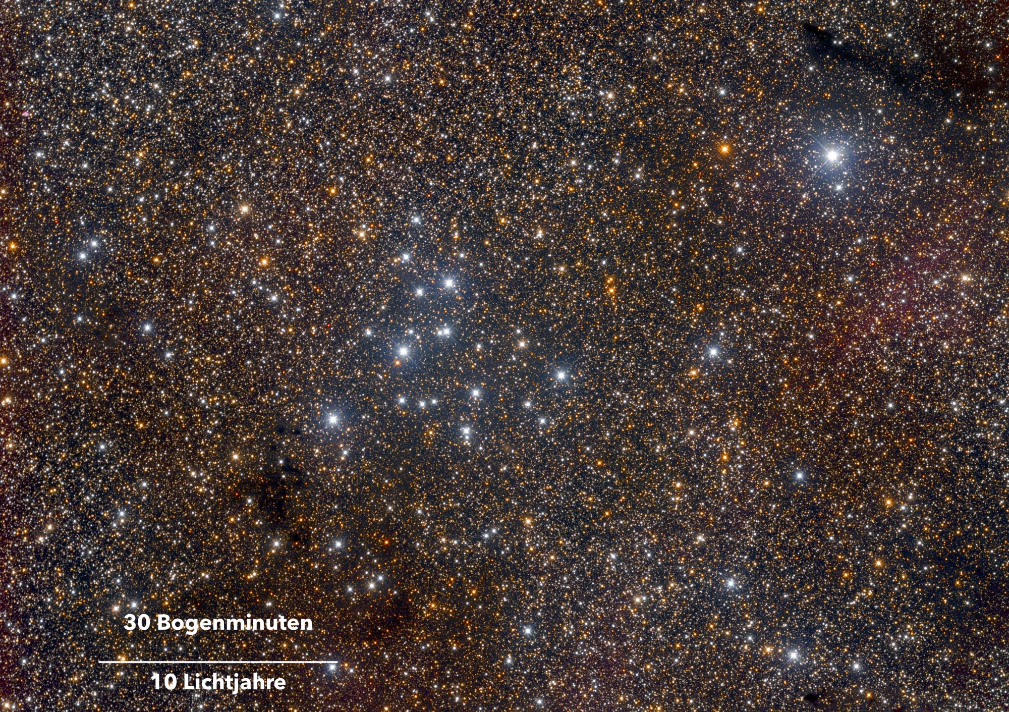 Ein dichtes Sternenfeld im Weltraum, das zahlreiche leuchtende Sterne in verschiedenen Helligkeiten zeigt. In der unteren linken Ecke befindet sich eine Skala mit der Beschriftung "30 Bogenminuten" und "10 Lichtjahre", die die Größenverhältnisse im Bild verdeutlicht. Der Hintergrund ist dunkel, wodurch die Sterne deutlich hervortreten.