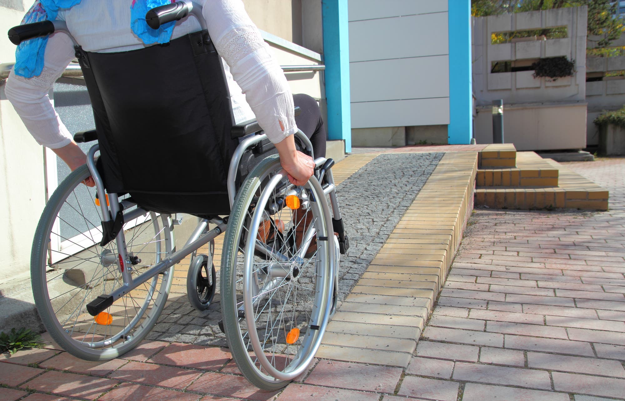 Rollstuhlfahrerin vor Rollstuhlrampe.