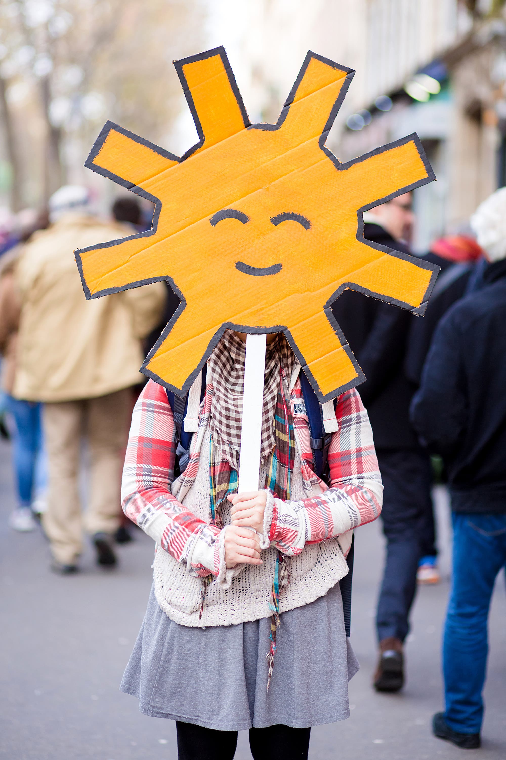 Demonstrantin auf einer Klimaschutz-Demo hält sich eine gelbe Sonne vor's Gesicht