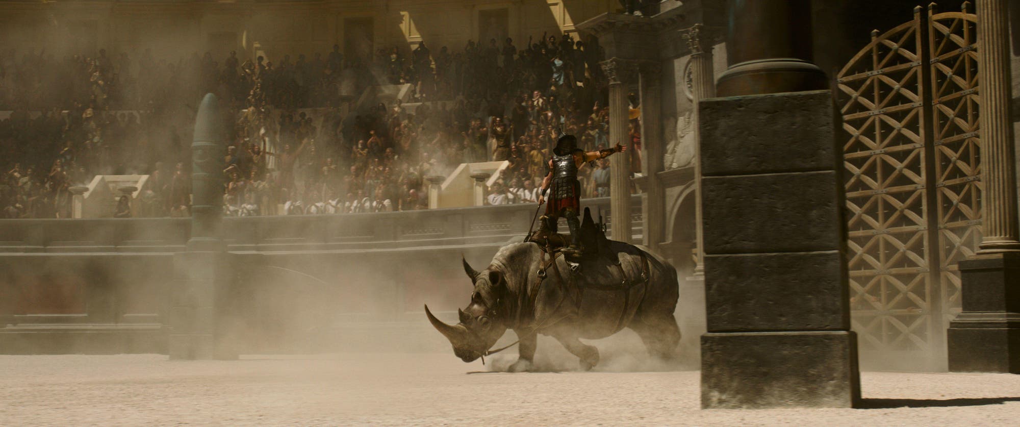 Szene aus »Gladiator II«: Ein Gladiator kommt auf einem gesattelten Nashorn stehend in die Arena.