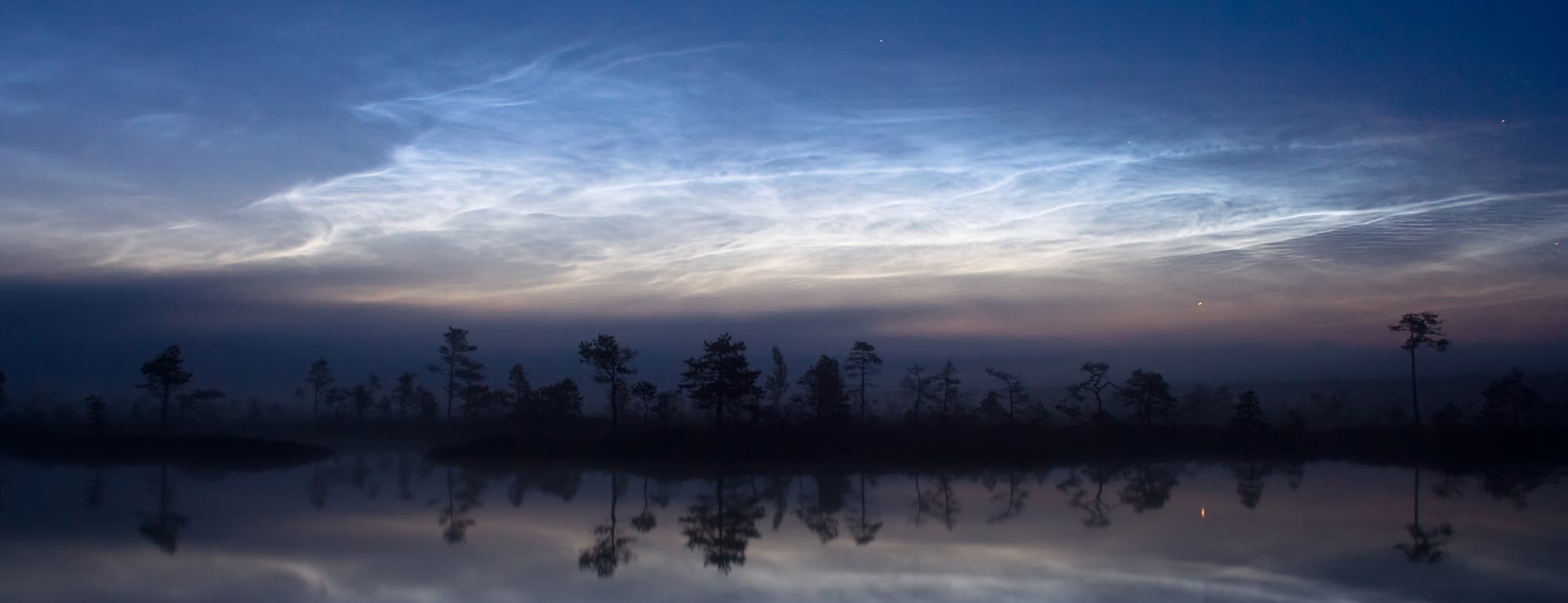 Leuchtende Nachtwolken über einem See