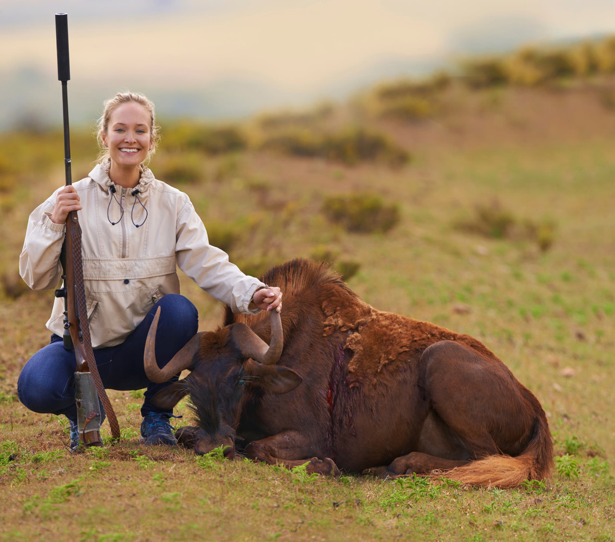 Eine Jägerin posiert mit einem erlegten Gnu, einer häufigen Antilopenart.