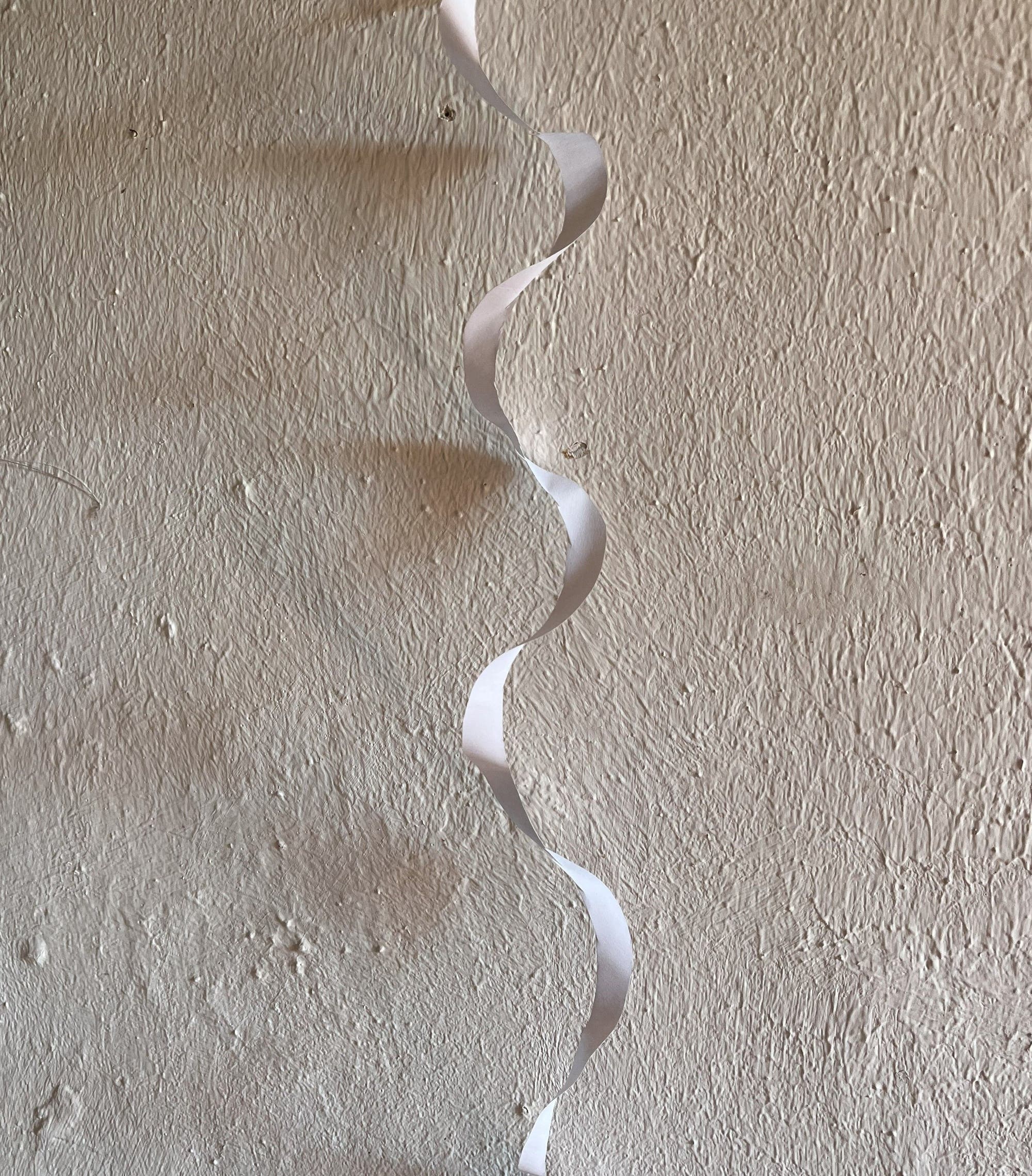Ein spiralförmig ausgeschnittener Streifen Papier kräuselt sich beim Aufhängen