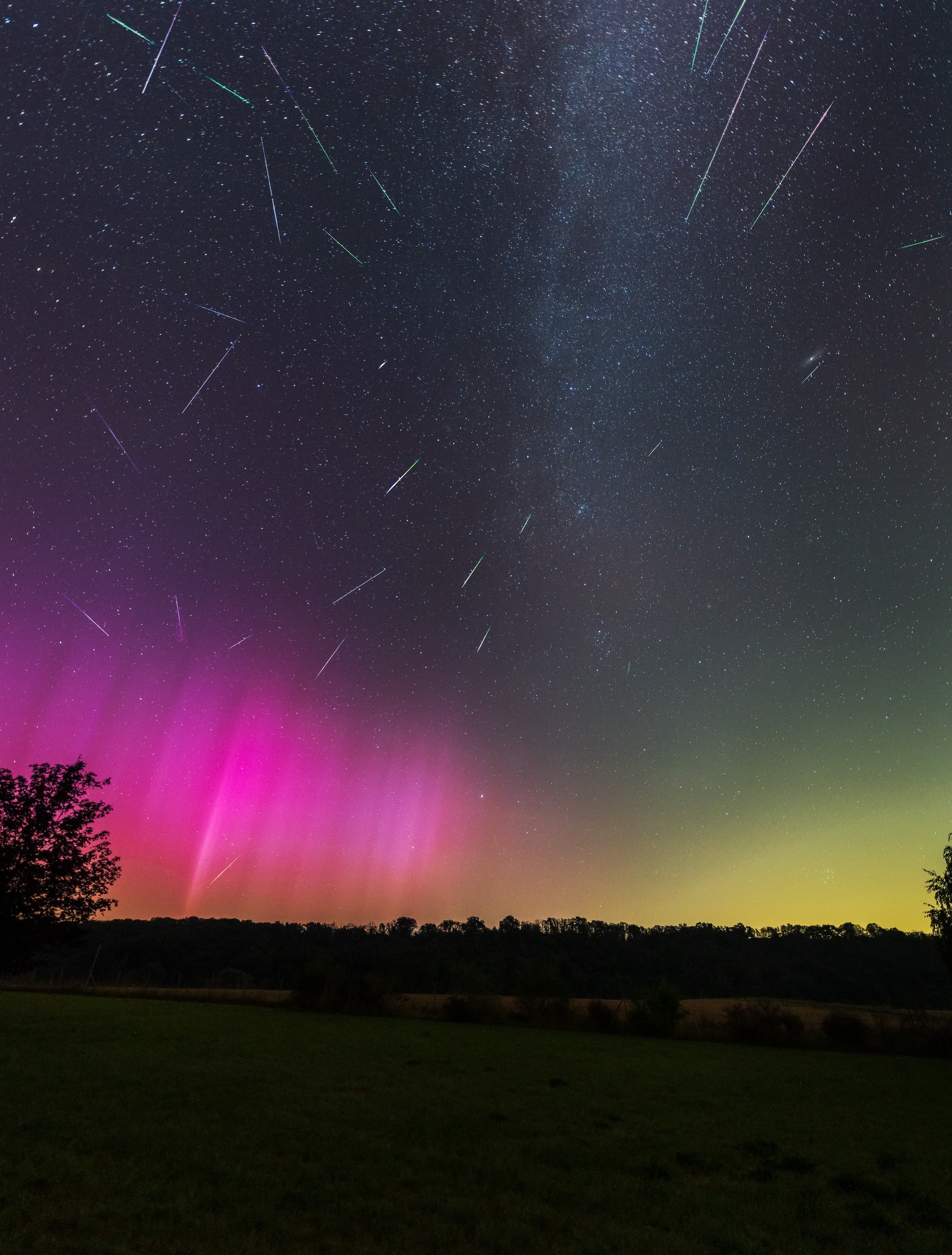 Polarlichter und Meteore des Perseidenstroms über einer nächtlichen Landschaft