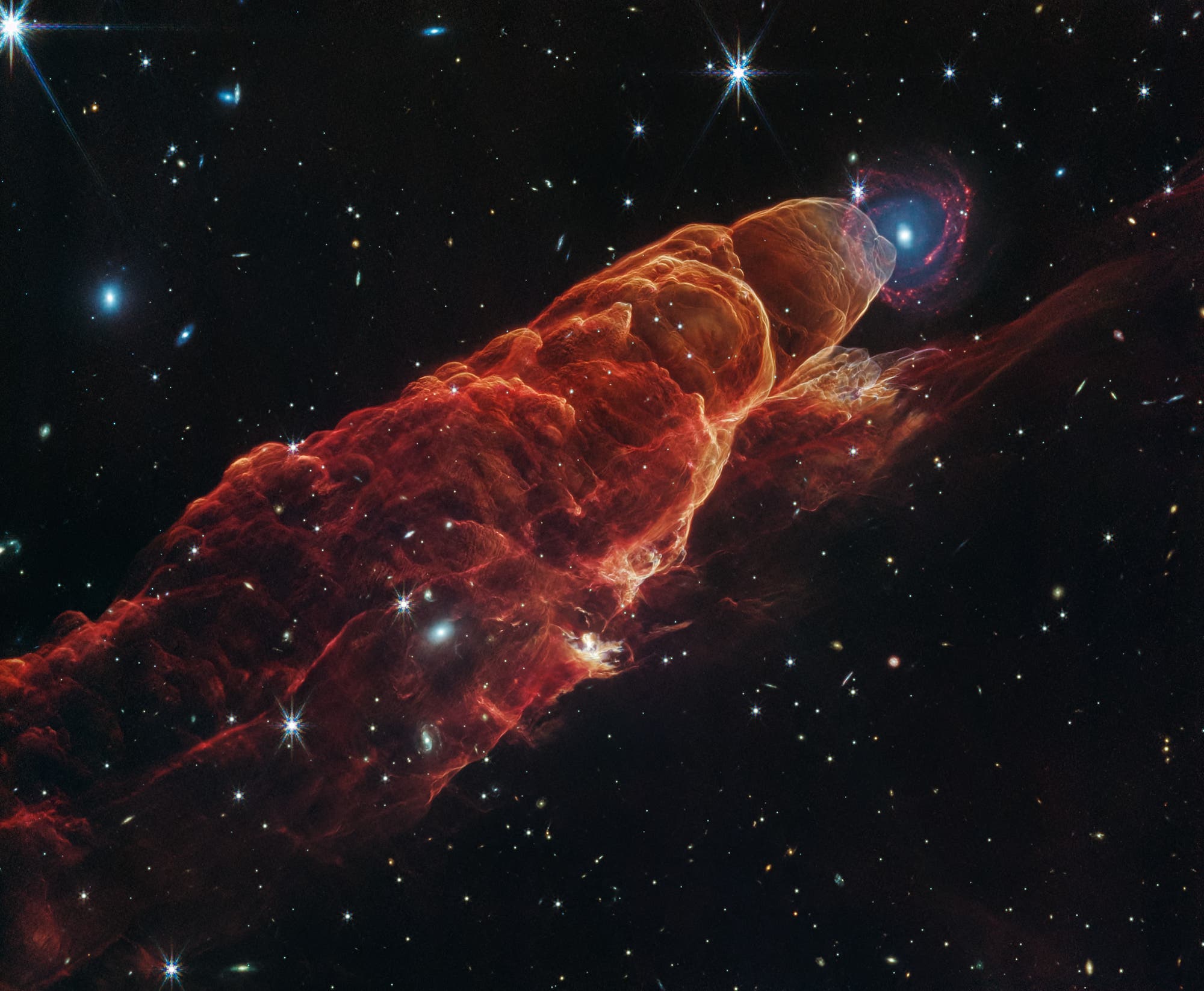 Ein beeindruckendes Bild zeigt das Herbig-Haro-Objekt HH 449/50, eine leuchtende Gaswolke. Die Wolke hat eine rötliche Färbung und erstreckt sich diagonal über das Bild. Im Hintergrund sind zahlreiche Sterne und Galaxien sichtbar, die den tiefen, dunklen Weltraum darstellen. Ein beeindruckendes Bild zeigt das Herbig-Haro-Objekt HH 449/50, eine leuchtende Gaswolke. Die Wolke hat eine rötliche Färbung und erstreckt sich diagonal über das Bild. Im Hintergrund sind zahlreiche Sterne und Galaxien sichtbar, die den tiefen, dunklen Weltraum darstellen.