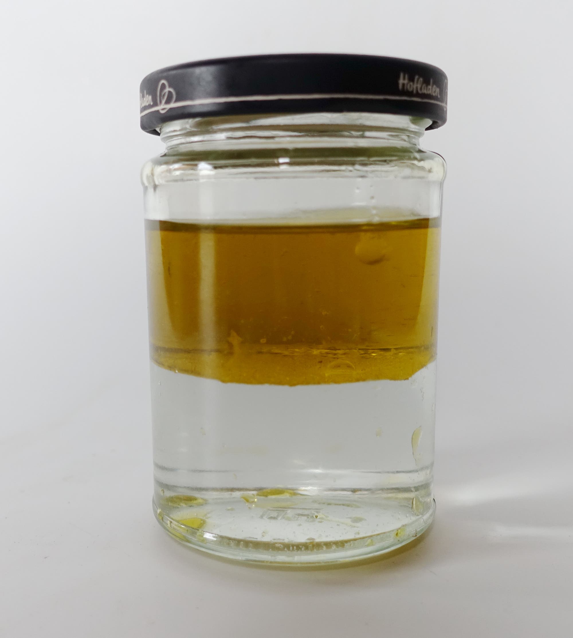 Öl treibt auf Wasser in einem Glas