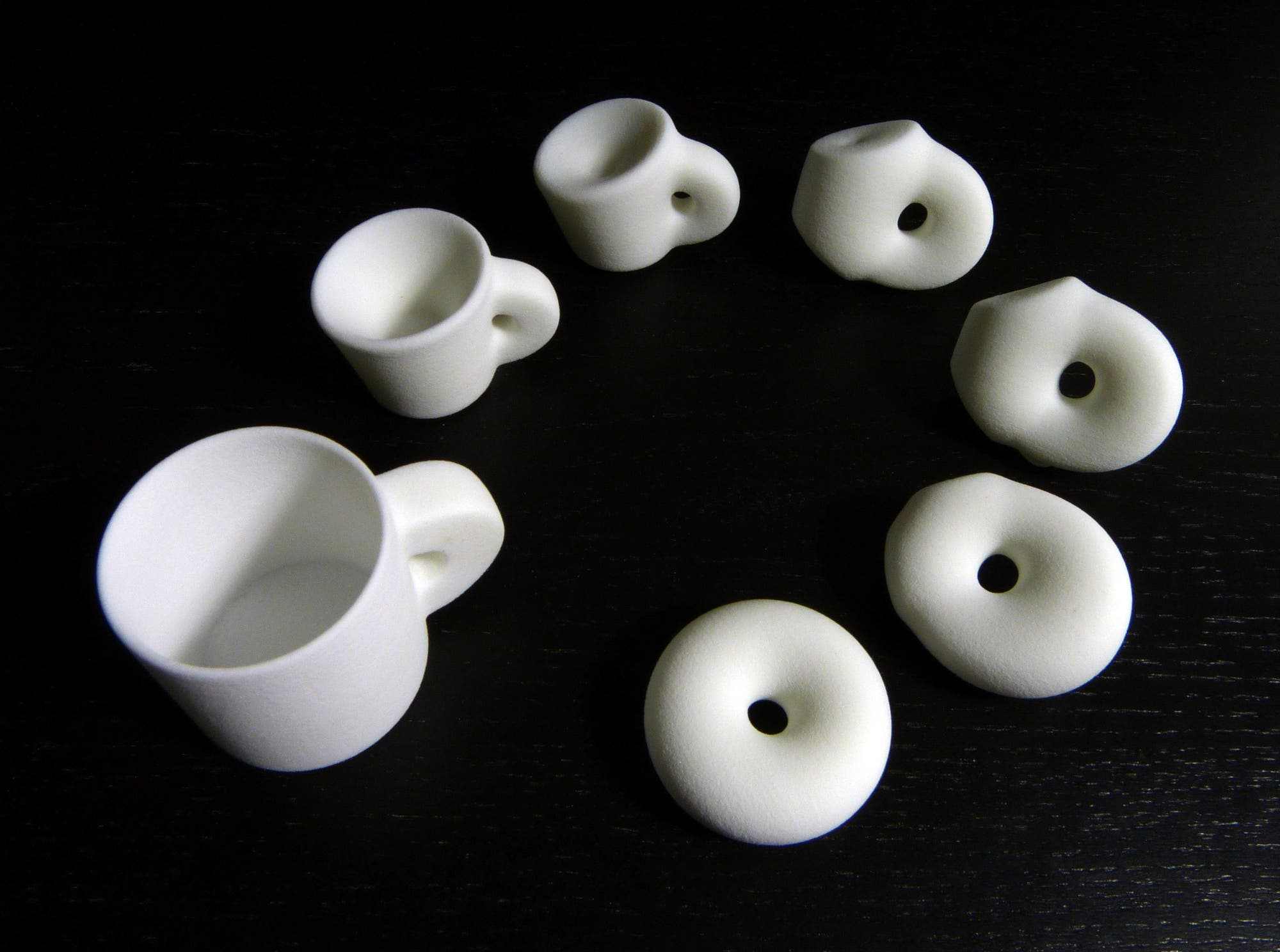 Durch einfaches Kneten kann man eine Tasse zu einem Donut verformen. Darum sind beide Objekte topologisch gesehen gleich.
