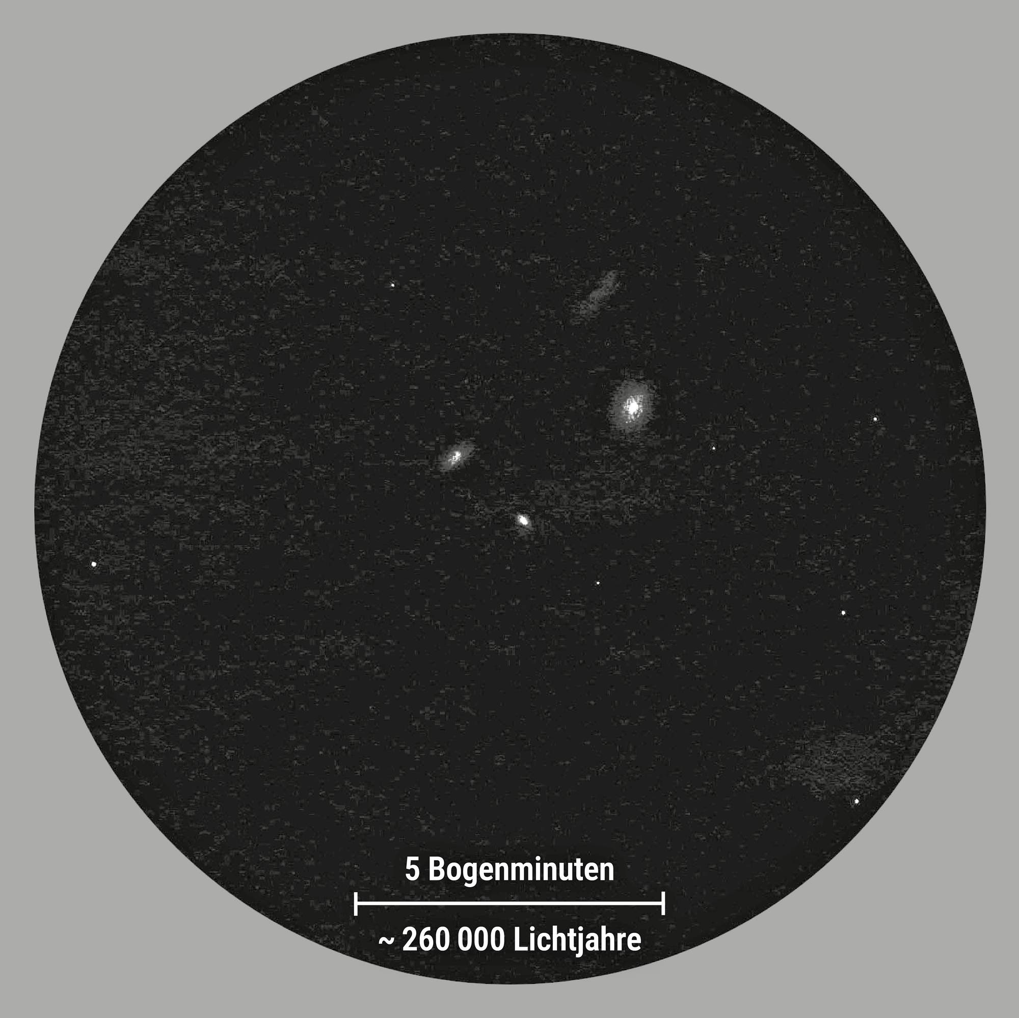 Zeichnung von vier Galaxien, die als verschwommene hellen Flecken vor einem schwarzem Hintergrund erscheinen. Ein paar wenige Sterne sind ebenfalls abgebildet.