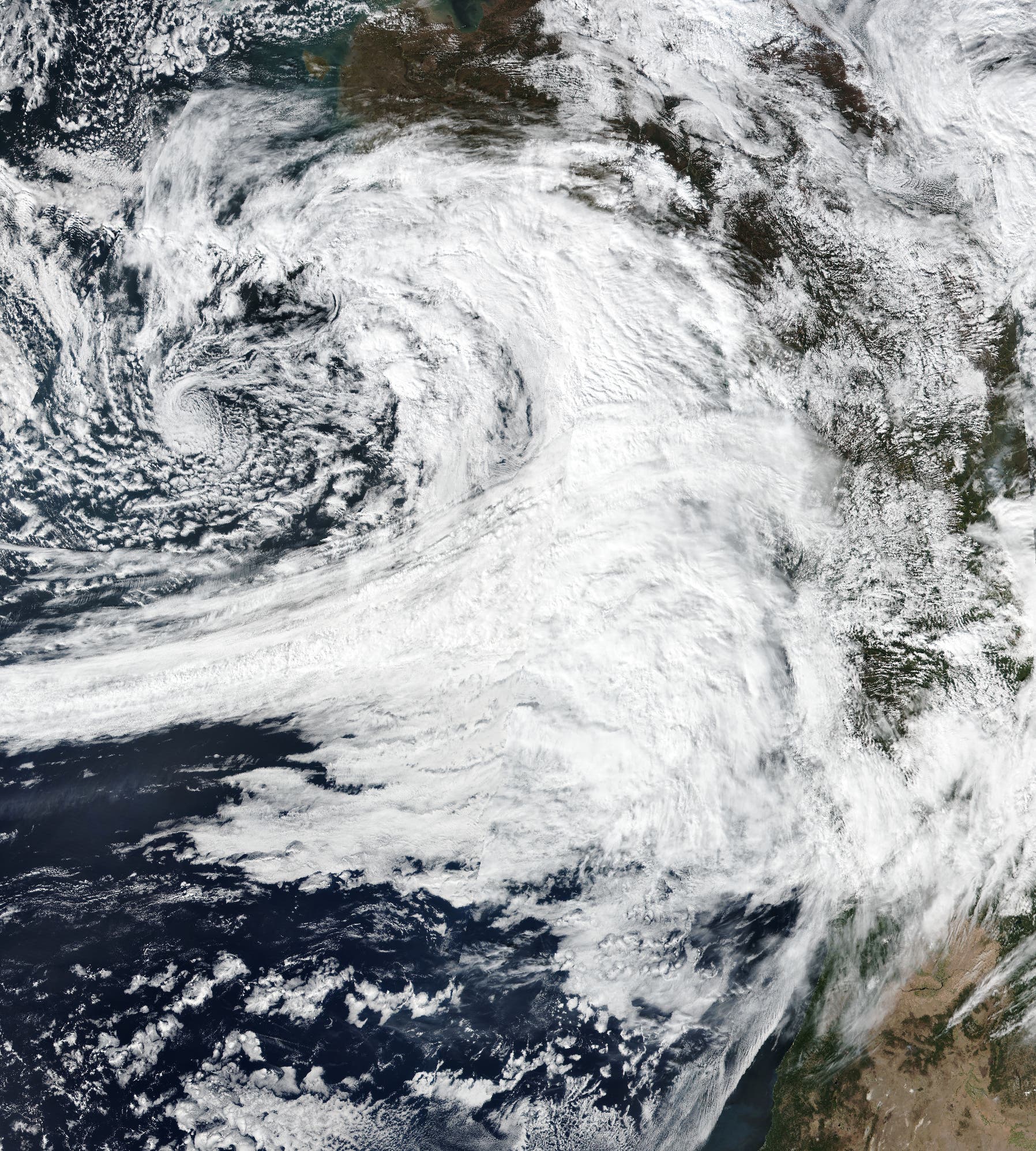 Ein starkes Wolkenband in Weiß auf dem Satellitenbild reicht vom dunkelblauen Pazifik bis an die Küste Nordamerikas. Der Kontinent ist am rechten Bildrand in Grün- und Brauntönen zu erkennen.