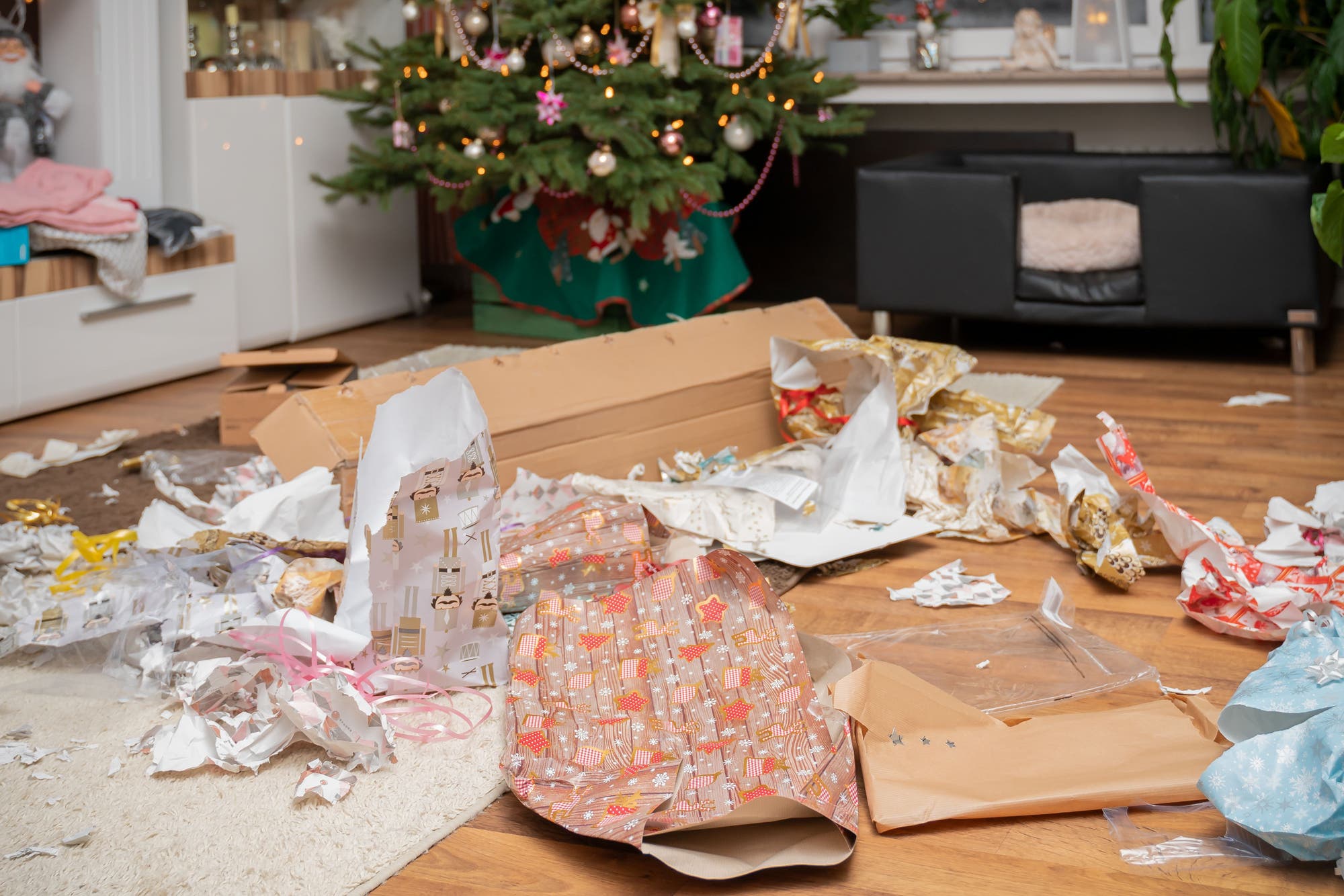 Ein Haufen zerrissenes Geschenkpapier liegt unterm Weihnachtsbaum