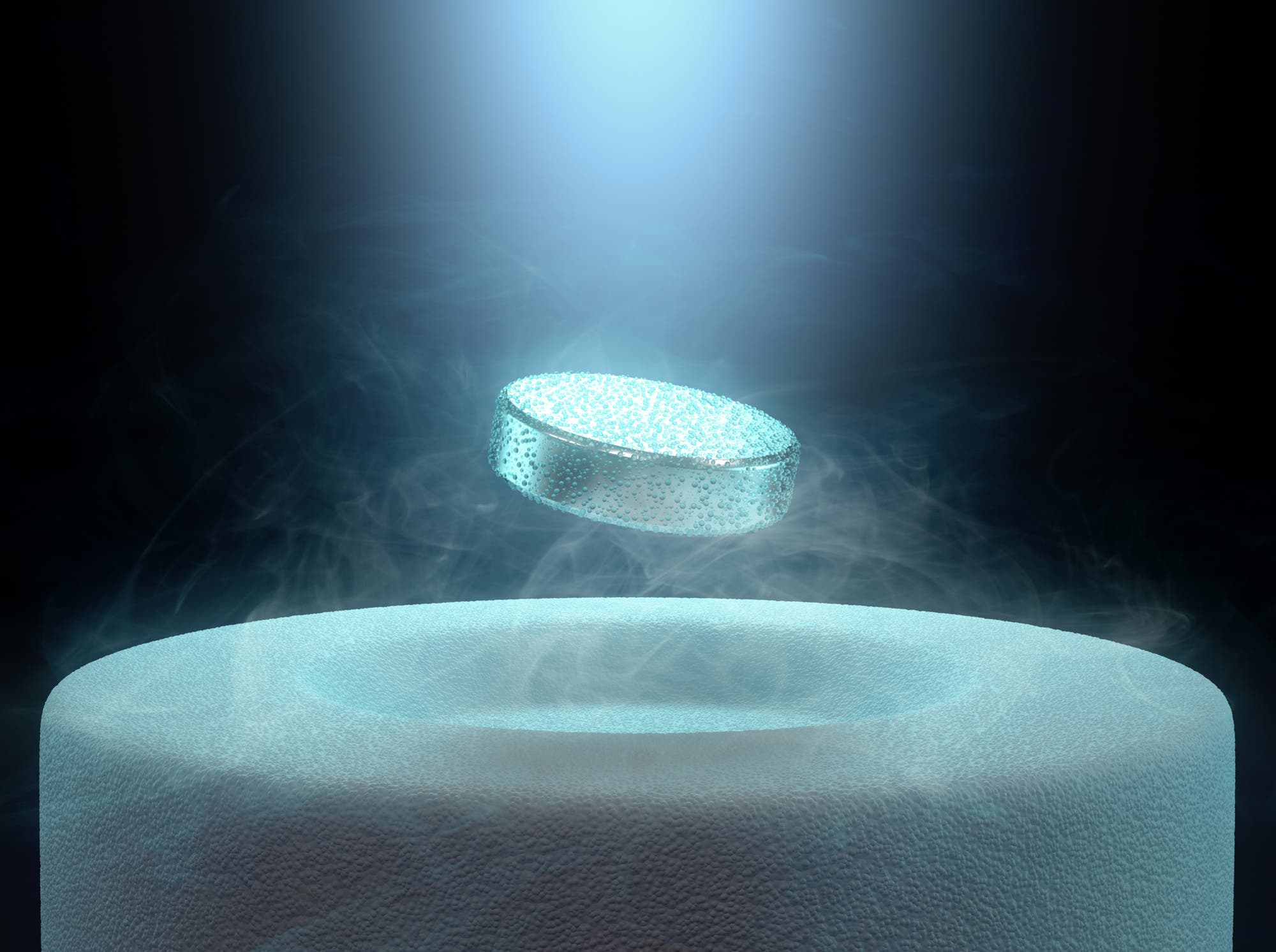 Eine runde, metallische Scheibe schwebt über einem zylinderförmigen, eisigen Podest, umgeben von Nebel. Ein Lichtstrahl beleuchtet die Szene von oben, was auf ein Experiment mit Supraleitung oder Magnetismus hinweist. Keine Menschen sind im Bild zu sehen.