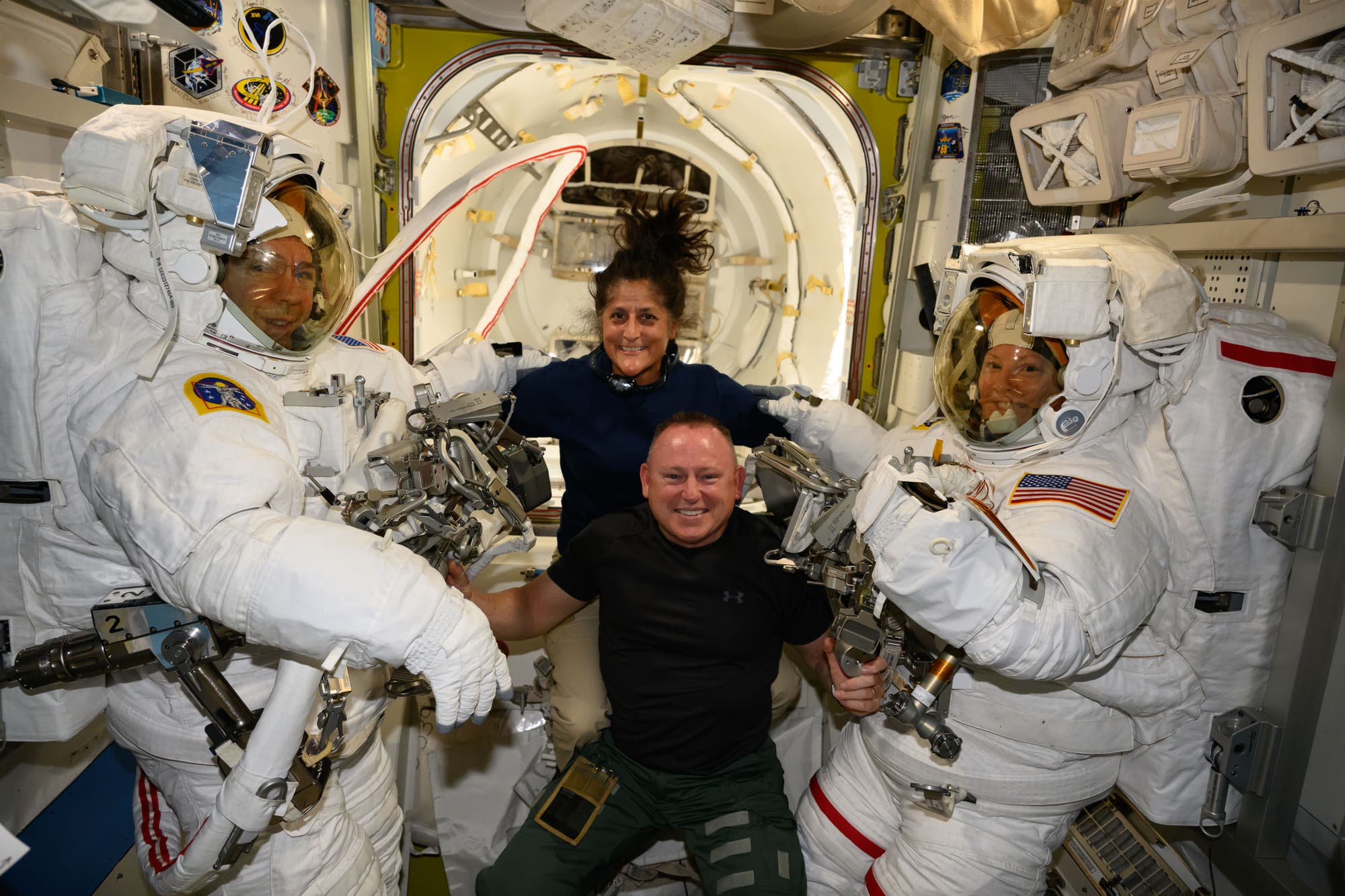 Die beiden Starliner-Astronauten posieren mit zwei Astronauten im Raumanzug an Bord der ISS