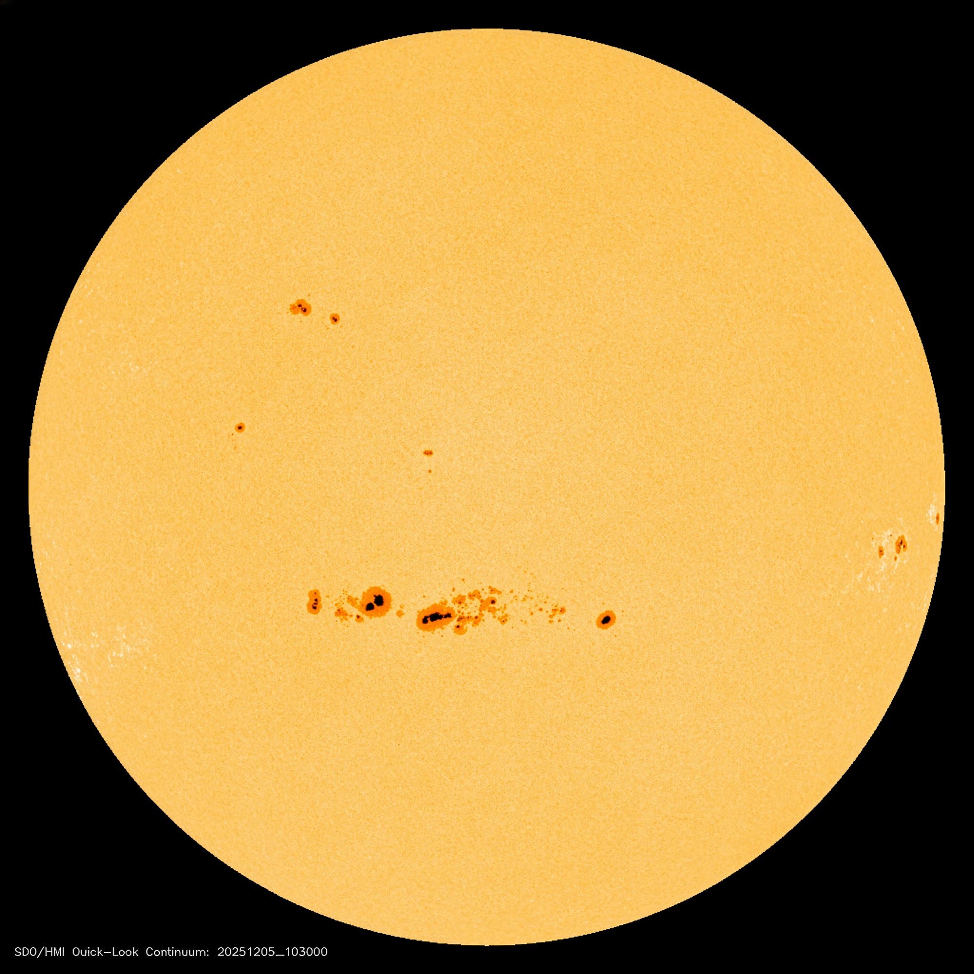 Eine Abbildung der Sonnenscheibe, die Sonnenflecken auf ihrer Oberfläche zeigt. Die Sonnenflecken erscheinen als dunkle Bereiche auf der ansonsten hellen Sonnenscheibe. Unten links im Bild befindet sich der Text "SDO/HMI Quick–Look Continuum: 20251205_103000", der auf das Datum und die Quelle der Aufnahme hinweist. Eine Abbildung der Sonnenscheibe, die Sonnenflecken auf ihrer Oberfläche zeigt. Die Sonnenflecken erscheinen als dunkle Bereiche auf der ansonsten hellen Sonnenscheibe. Unten links im Bild befindet sich der Text "SDO/HMI Quick–Look Continuum: 20251205_103000", der auf das Datum und die Quelle der Aufnahme hinweist.