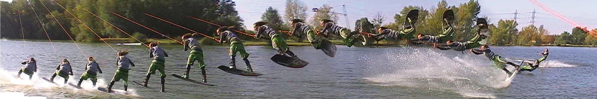 Eine Person führt eine Abfolge von Tricks auf einem Wakeboard auf einem See aus. Die Bilder zeigen die Bewegung von links nach rechts, während die Person in die Luft springt und eine Drehung vollführt, bevor sie wieder ins Wasser eintaucht. Im Hintergrund sind Bäume und Stromleitungen zu sehen.