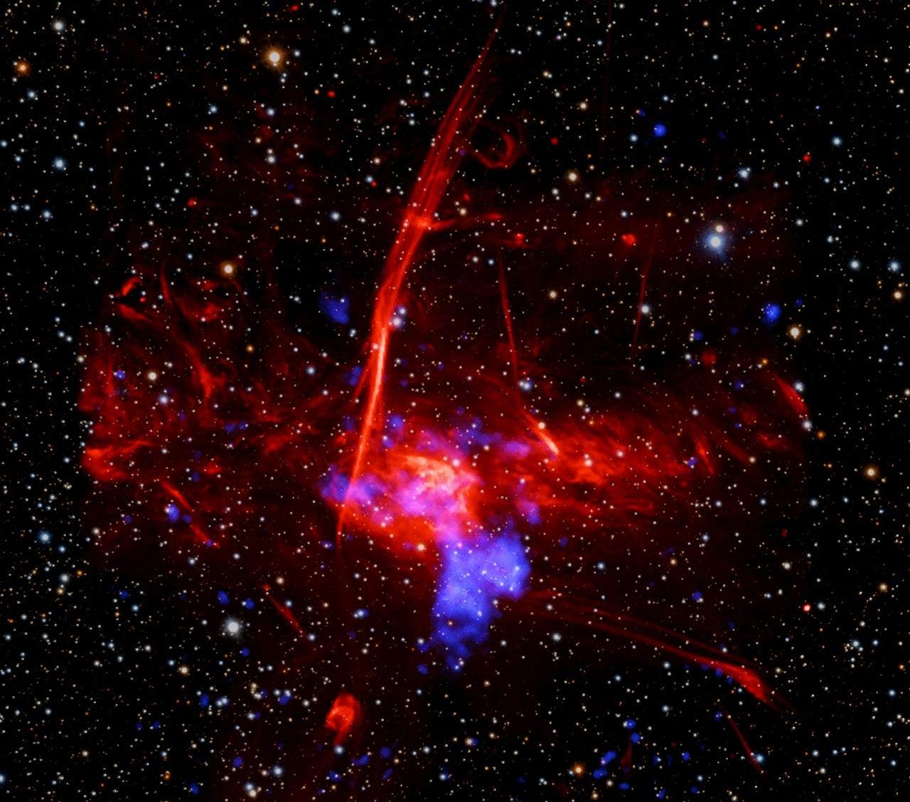 Ein farbenfrohes astronomisches Bild zeigt eine dichte Ansammlung von Sternen und interstellarem Gas im Weltraum. Rote und blaue Nebelstrukturen durchziehen das Bild, umgeben von zahlreichen leuchtenden Sternen auf schwarzem Hintergrund. Die roten Filamente und blauen Wolken deuten auf komplexe kosmische Prozesse hin. Das Bild vermittelt die Weite und Schönheit des Universums. Ein farbenfrohes astronomisches Bild zeigt eine dichte Ansammlung von Sternen und interstellarem Gas im Weltraum. Rote und blaue Nebelstrukturen durchziehen das Bild, umgeben von zahlreichen leuchtenden Sternen auf schwarzem Hintergrund. Die roten Filamente und blauen Wolken deuten auf komplexe kosmische Prozesse hin. Das Bild vermittelt die Weite und Schönheit des Universums.