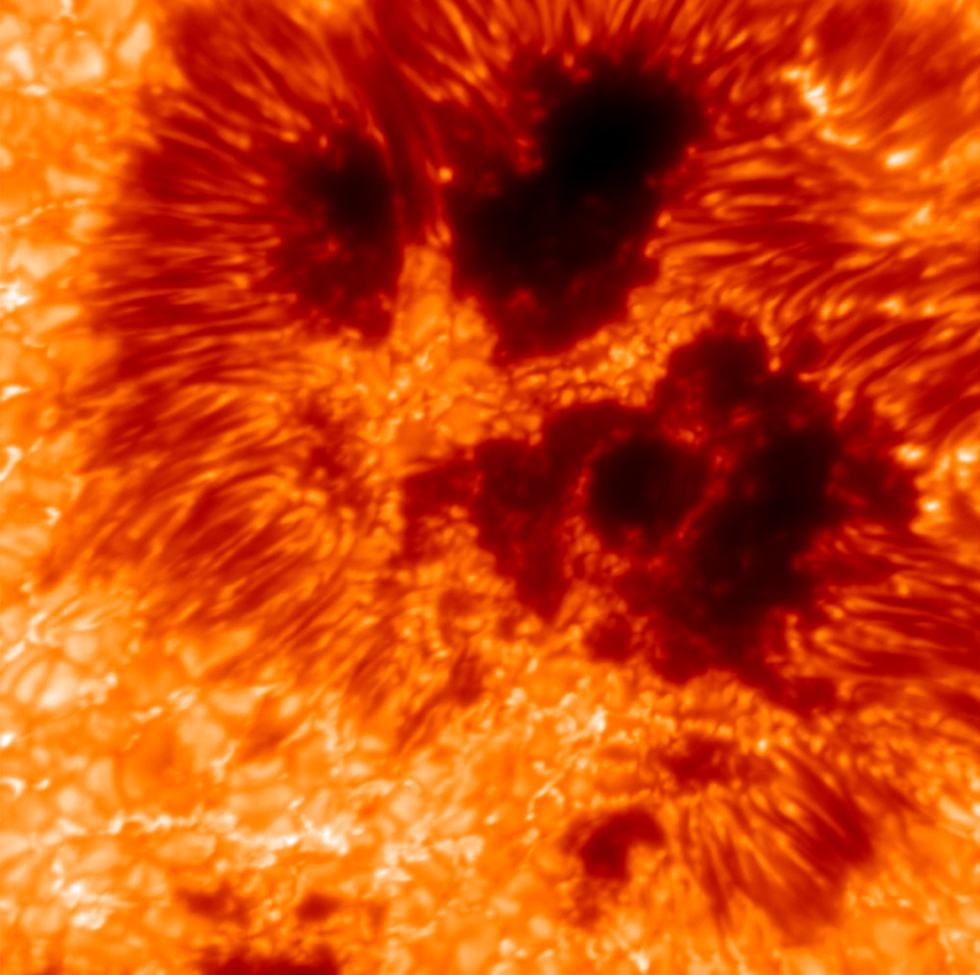 Nahaufnahme einer Sonnenoberfläche mit dunklen Sonnenflecken und leuchtenden, wirbelnden Plasmamustern in Rot- und Orangetönen. Die Textur zeigt die dynamische Aktivität der Sonne. Nahaufnahme einer Sonnenoberfläche mit dunklen Sonnenflecken und leuchtenden, wirbelnden Plasmamustern in Rot- und Orangetönen. Die Textur zeigt die dynamische Aktivität der Sonne.