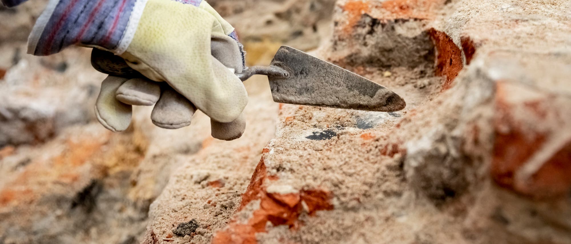 Babis Papasavvas, Restaurator und Grabungshelfer, befreit im archäologischen Grabungsfeld im Mühlendamm am Ort des historischen Molkenmarktes mit einer Kelle Steine von Sand und Schutt