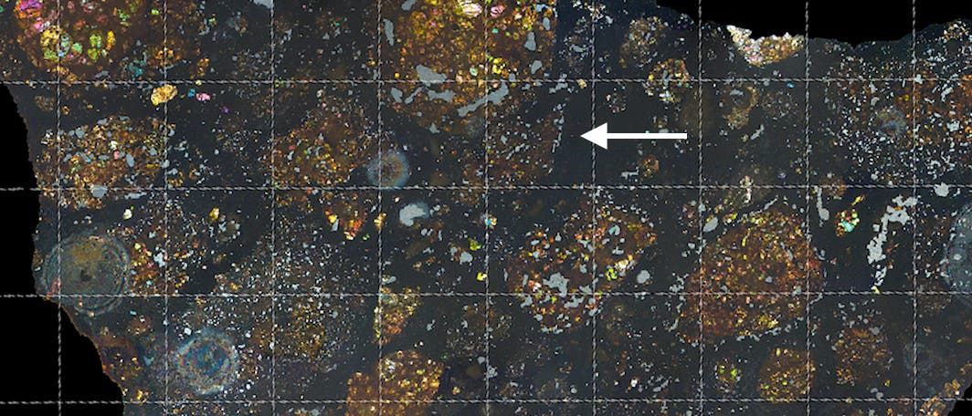 Der Mutterkörper von LaPaz Icefield 02342 wurde nach seiner Entstehung kaum verändert. Der Pfeil im Bild zeigt auf die Stelle in diesem Dünnschliff, an der das winzige Kometenbruchstück verborgen ist. 