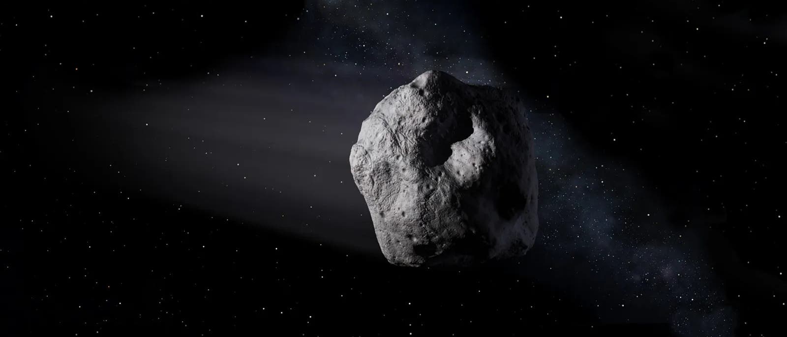 Un gran asteroide de forma irregular flota en el espacio, rodeado por un fondo de estrellas. El asteroide presenta una superficie rugosa parecida a un cráter. Al fondo se puede ver un tenue rastro de luz, probablemente causado por el reflejo de la luz del sol. La escena transmite una sensación de inmensidad y aislamiento en el universo.
