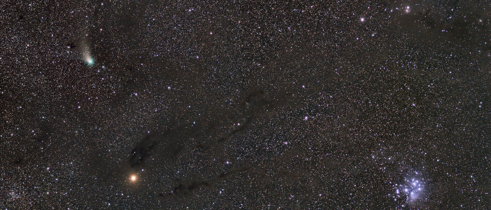 Ein weitl&auml;ufiges astronomisches Bild zeigt einen sternenreichen Nachthimmel. Links ist ein Komet mit einem leuchtenden Schweif zu sehen. Oben rechts befindet sich ein r&ouml;tlicher Nebel, w&auml;hrend unten rechts ein heller Sternhaufen erkennbar ist. Die Aufnahme vermittelt die Weite und Vielfalt des Universums.