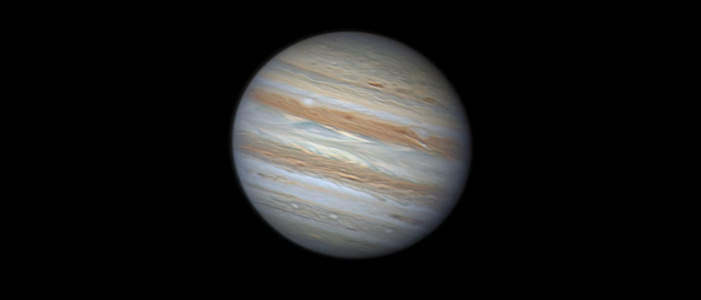 Die astronomische Amateuraufnahme zeigt den Planeten Jupiter mit seinen charakteristischen Wolkenb&auml;ndern in verschiedenen Braunt&ouml;nen und Wei&szlig;. Die Atmosph&auml;re des Planeten weist Wirbel und Streifen auf, die durch die schnelle Rotation des Planeten entstehen. Der Hintergrund ist schwarz.