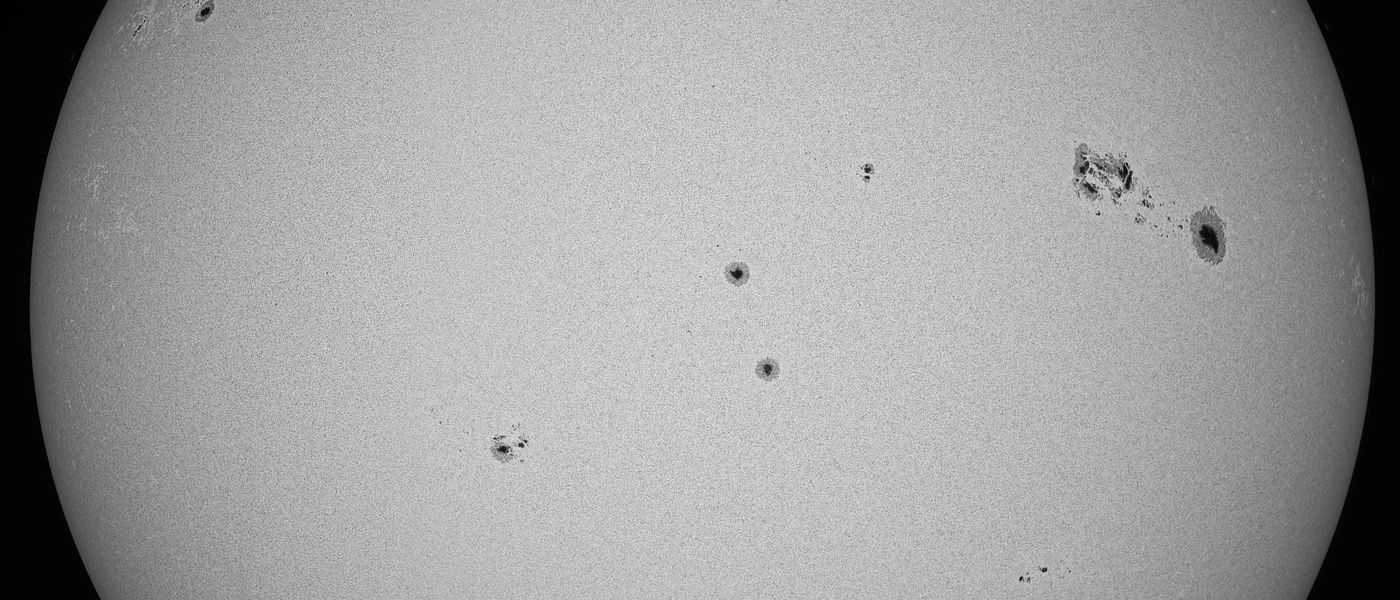 Imagen en blanco y negro de la superficie del sol con varias manchas solares de diferentes tamaños. Las manchas aparecen como áreas oscuras en la superficie brillante del sol. Esta imagen astronómica muestra la textura y estructura de la superficie del sol y resalta la distribución no uniforme de las manchas solares. Imagen en blanco y negro de la superficie del sol con varias manchas solares de diferentes tamaños. Las manchas aparecen como áreas oscuras en la superficie brillante del sol. Esta imagen astronómica muestra la textura y estructura de la superficie del sol y resalta la distribución no uniforme de las manchas solares.