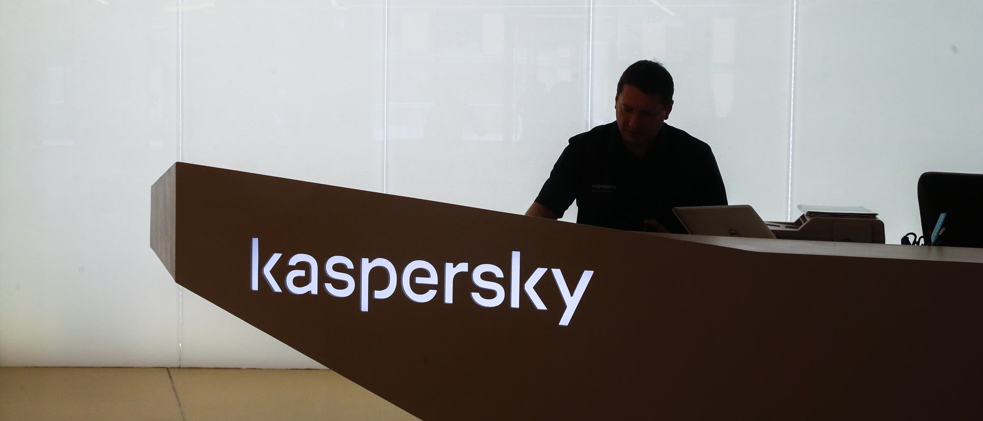 Ein Mann an einem dunklen Schreibtisch mit Kaspersky-Schriftzug.
