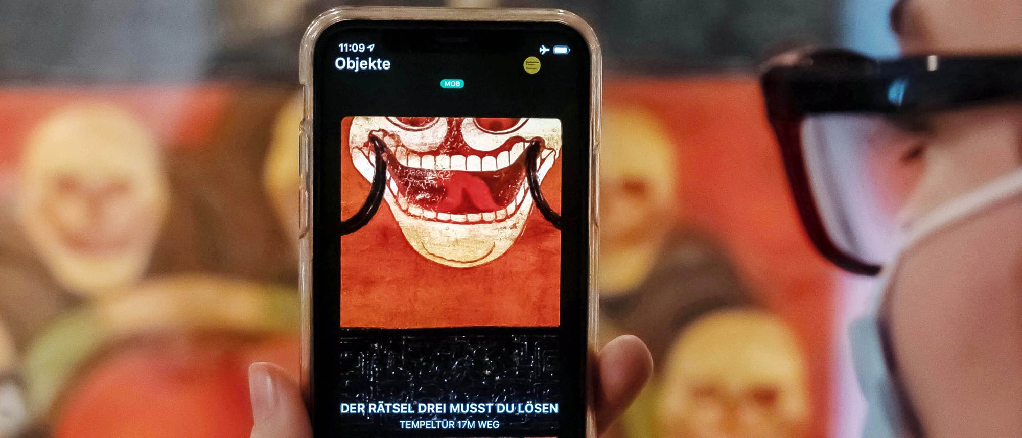 Im Badischen Landesmuseum wird vor einer Tempeltür aus Tibet aus dem 19. Jahrhundert auf einem Smartphone eine App gezeigt, mit der Museumsbesucher Kontakt zu Ausstellungsobjekten aufbauen können. 