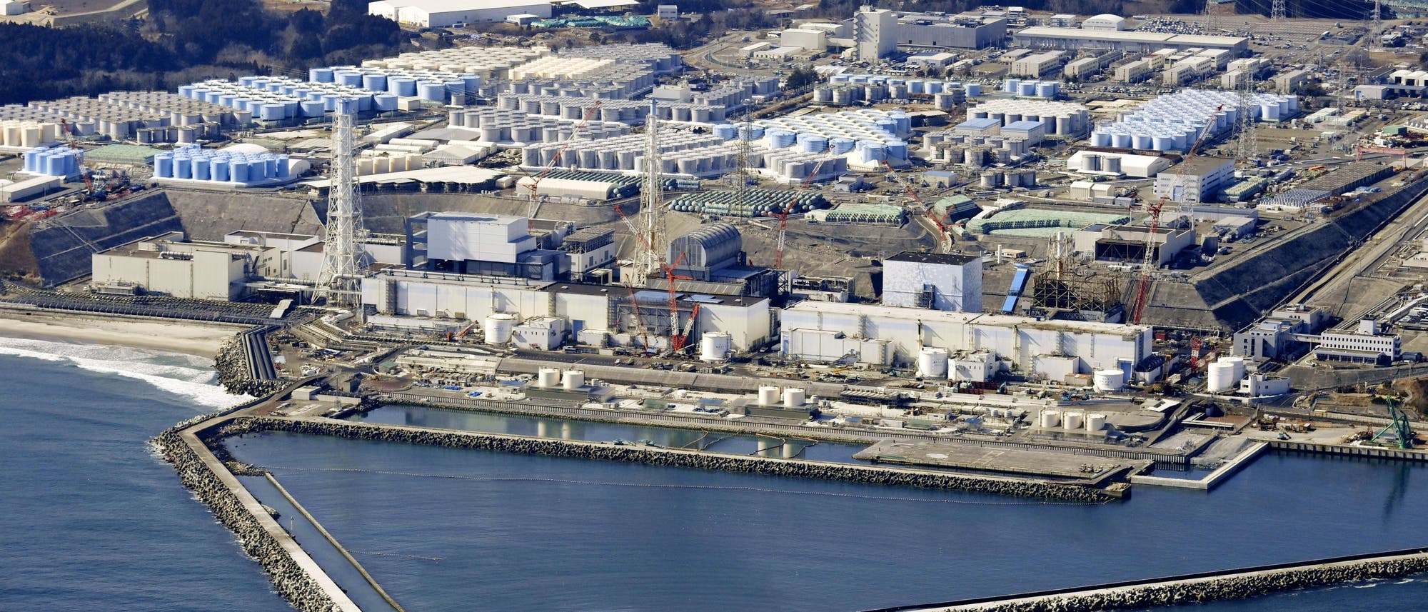 Luftbild des havarierten Kernkraftwerks Fukushima Daiichi mit Wassertanks im Hintergrund.