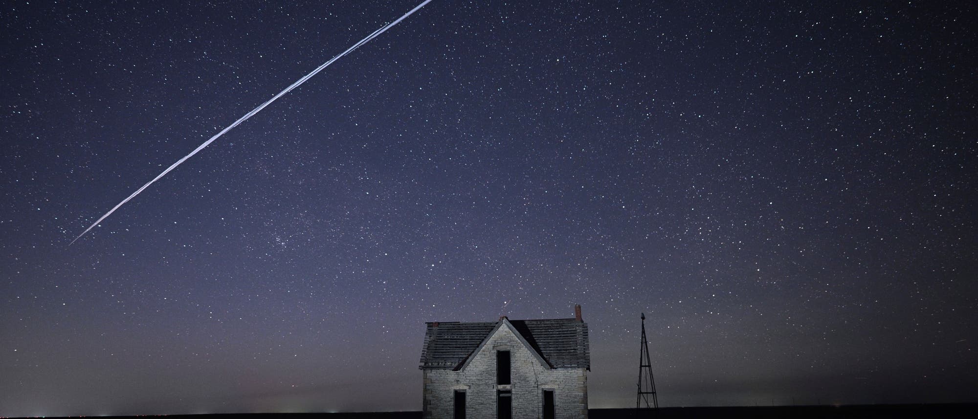 In diesem Foto, das am 6. Mai 2021 mit einer langen Belichtung aufgenommen wurde, zieht eine Reihe von SpaceX StarLink-Satelliten über ein altes Steinhaus in der Nähe von Florence.