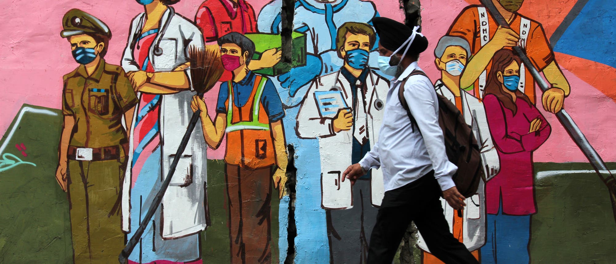 Ein Mann geht in Neu-Delhi, Indien, an einem Graffiti vorbei, das die Mitarbeiter des Gesundheitswesens würdigt.